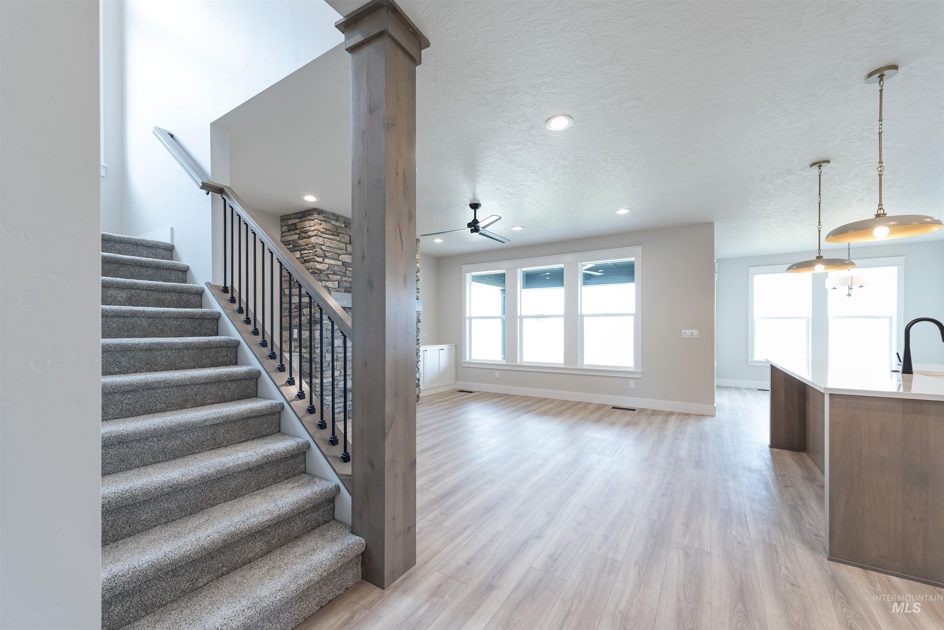 Stairs with wood finished floors, a textured ceiling, a ceiling fan, and recessed lighting