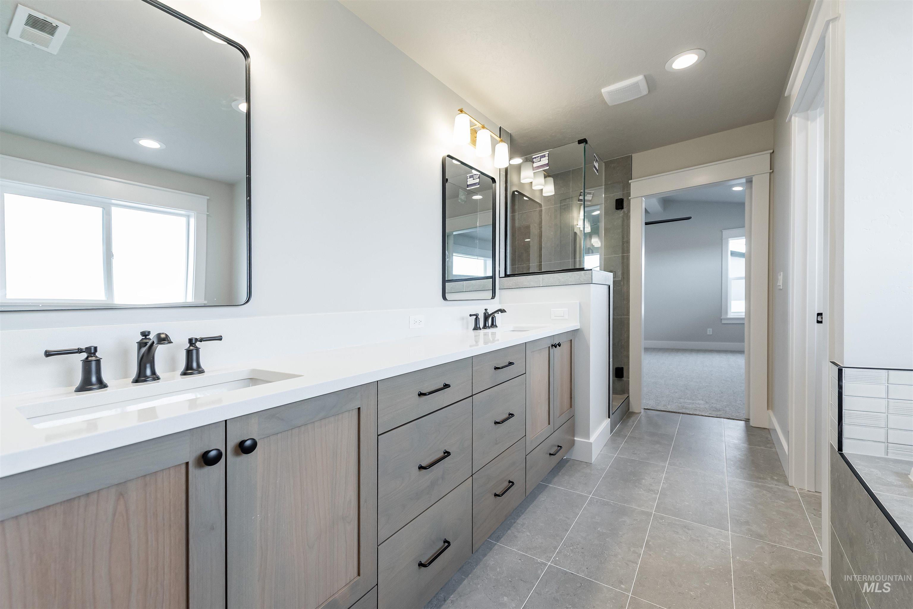 Full bathroom featuring double vanity, light tile patterned floors, a shower stall, and recessed lighting