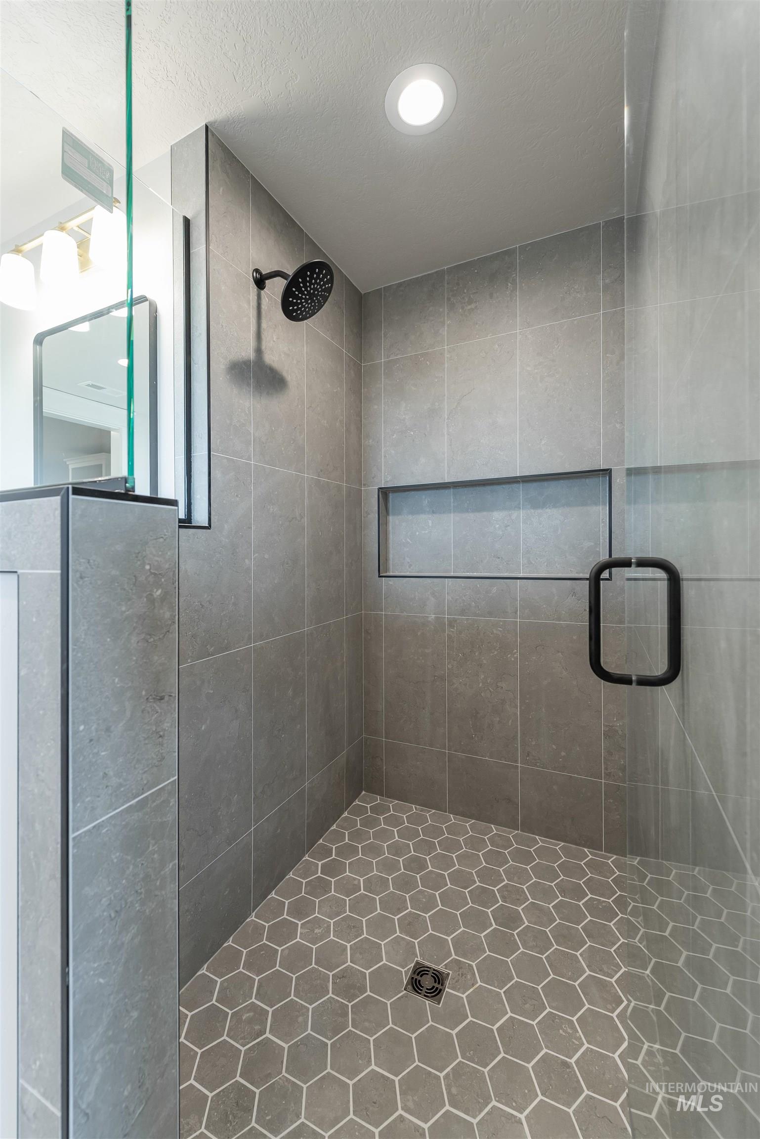 Bathroom featuring a shower stall, recessed lighting, and a textured ceiling