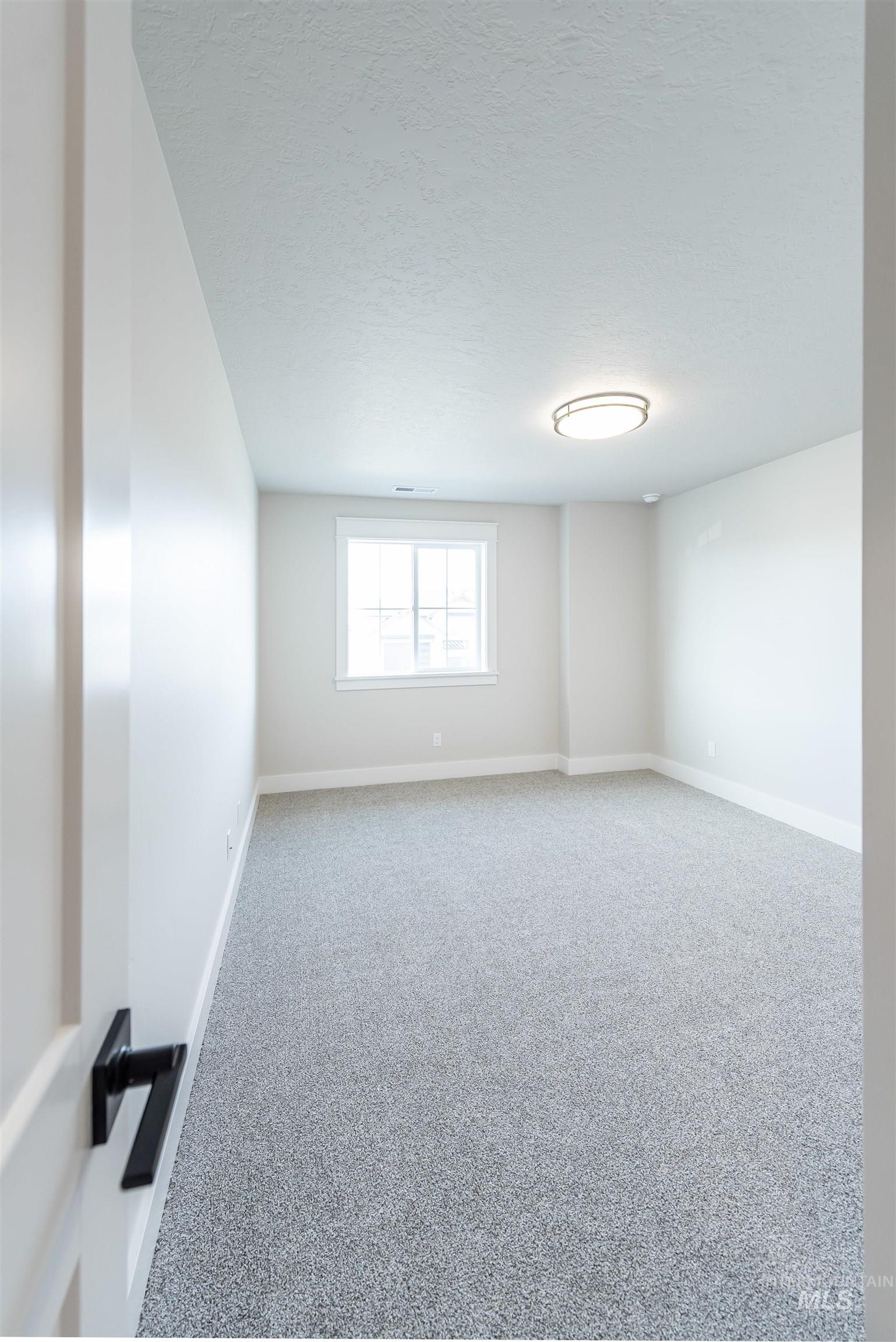 Empty room featuring a textured ceiling and carpet