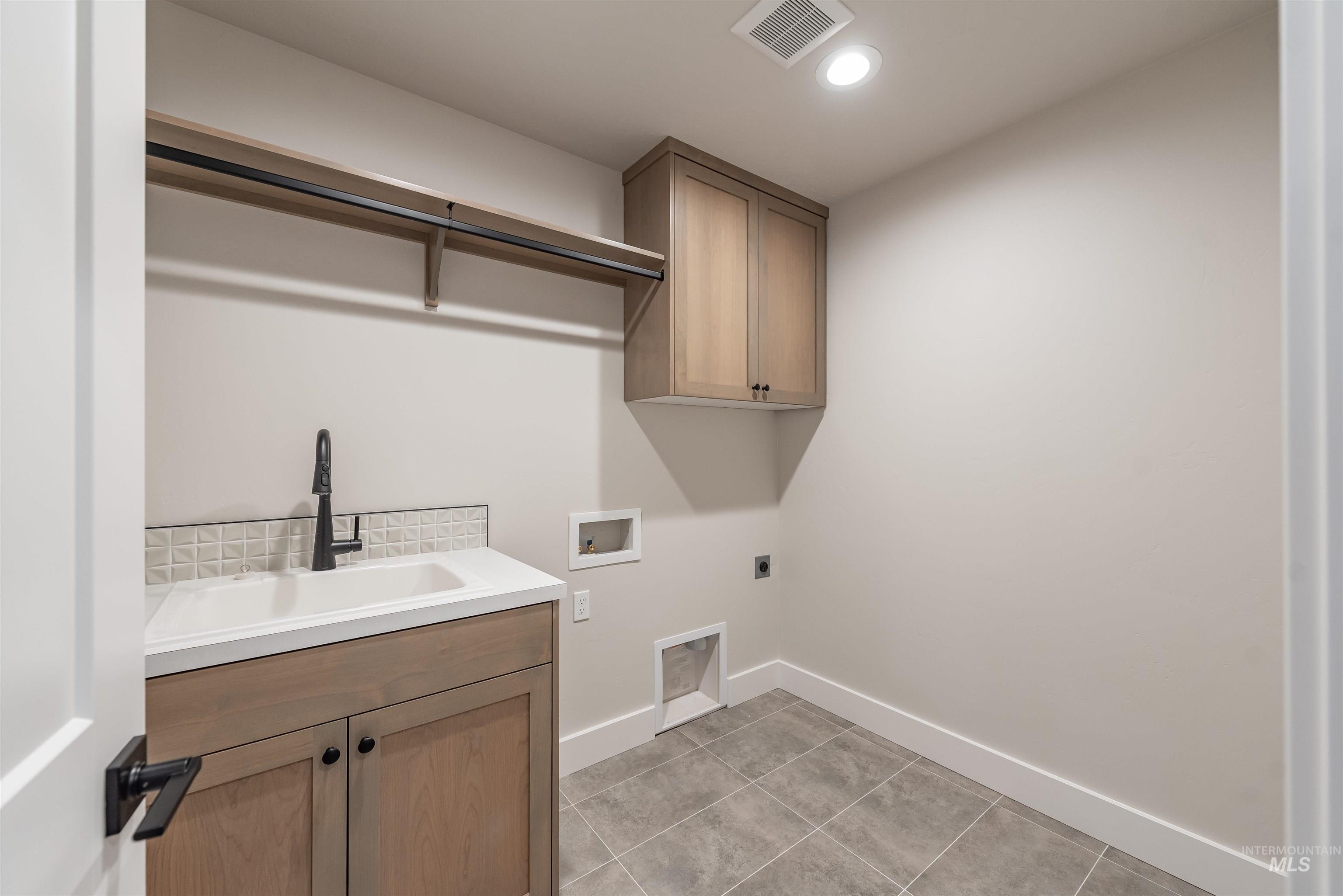 Washroom featuring cabinet space, washer hookup, hookup for an electric dryer, recessed lighting, and light tile patterned floors