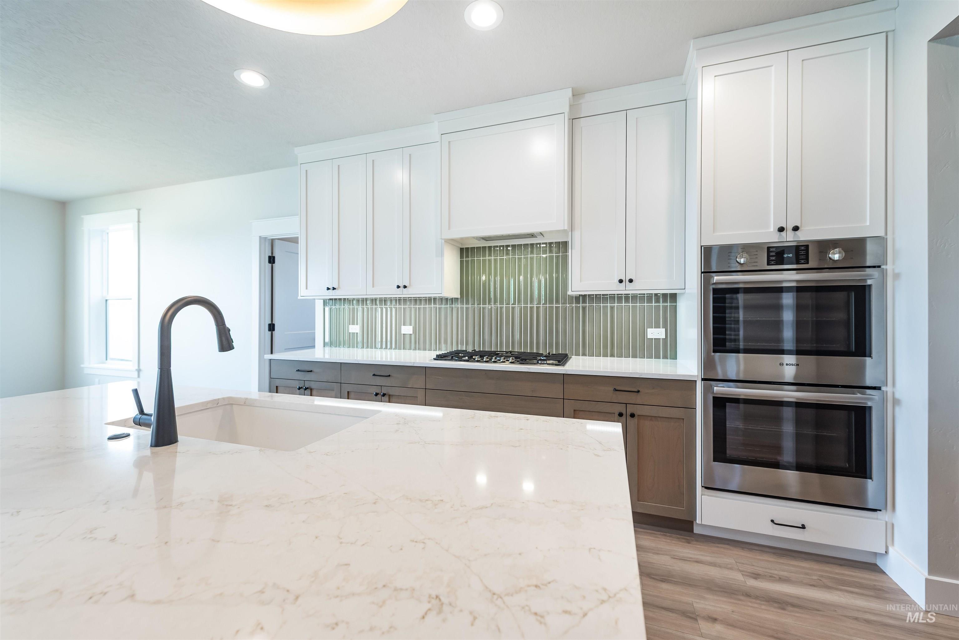 Kitchen featuring white cabinets, appliances with stainless steel finishes, light stone counters, backsplash, and recessed lighting