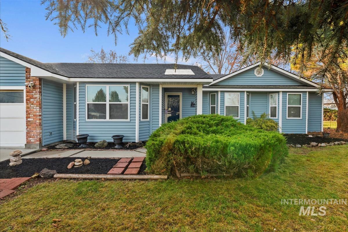 View of front of home with a front yard, roof with shingles, and solar panels