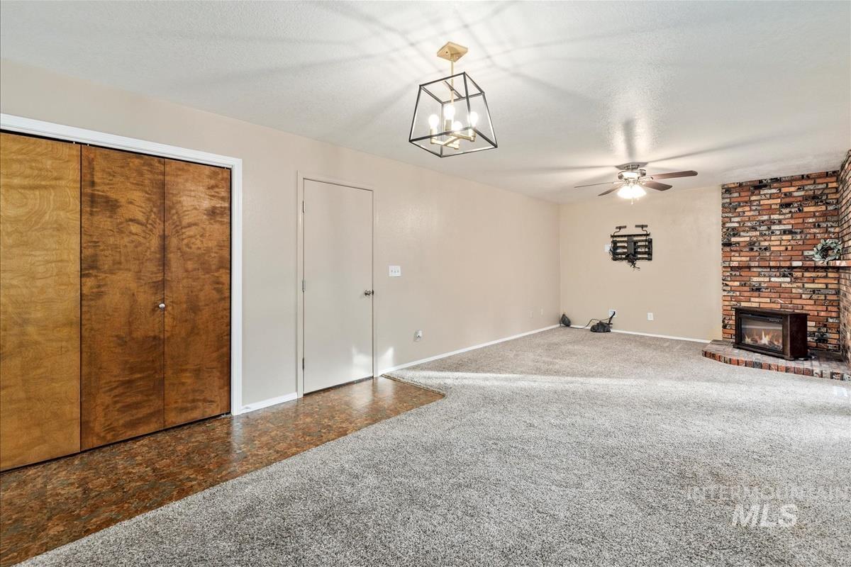 Unfurnished living room with carpet flooring, a ceiling fan, a chandelier, and a fireplace