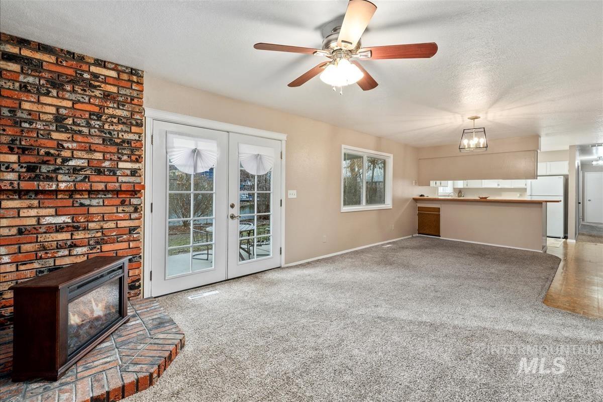 Unfurnished living room featuring light colored carpet, healthy amount of natural light, ceiling fan, a textured ceiling, and french doors