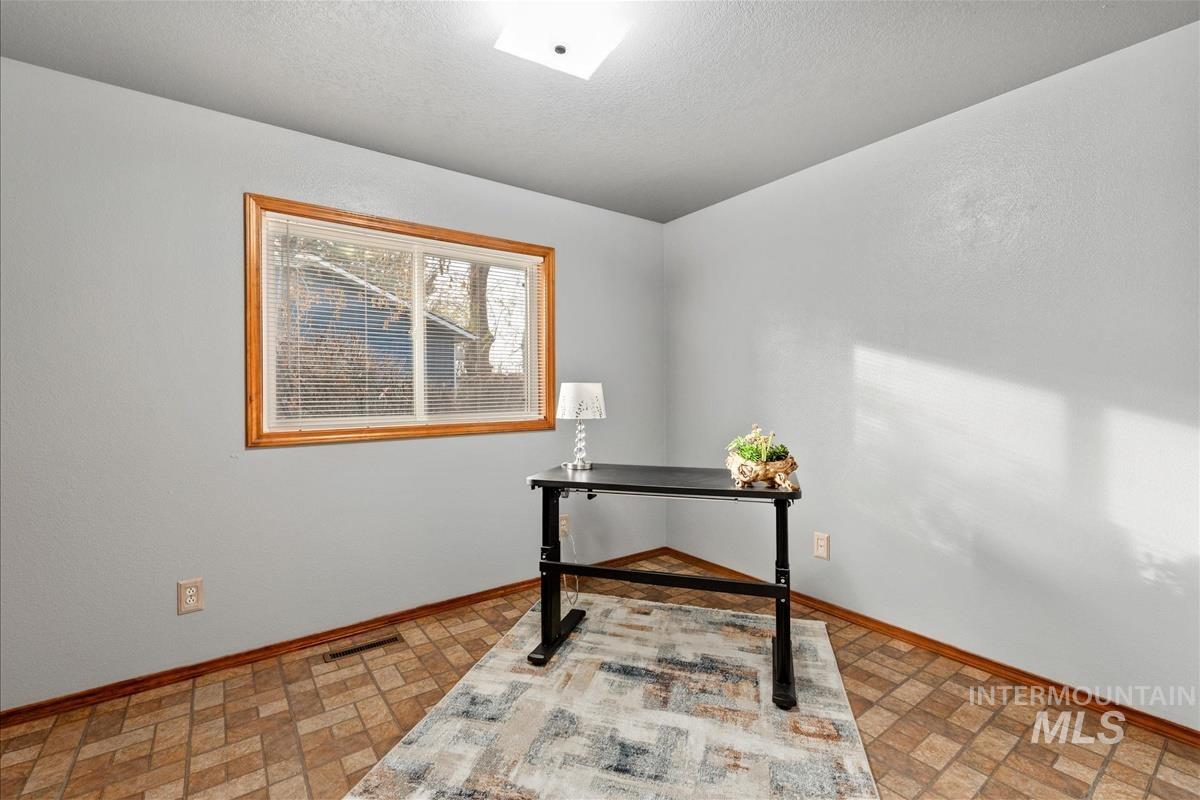 Office space featuring brick patterned floors and a textured ceiling