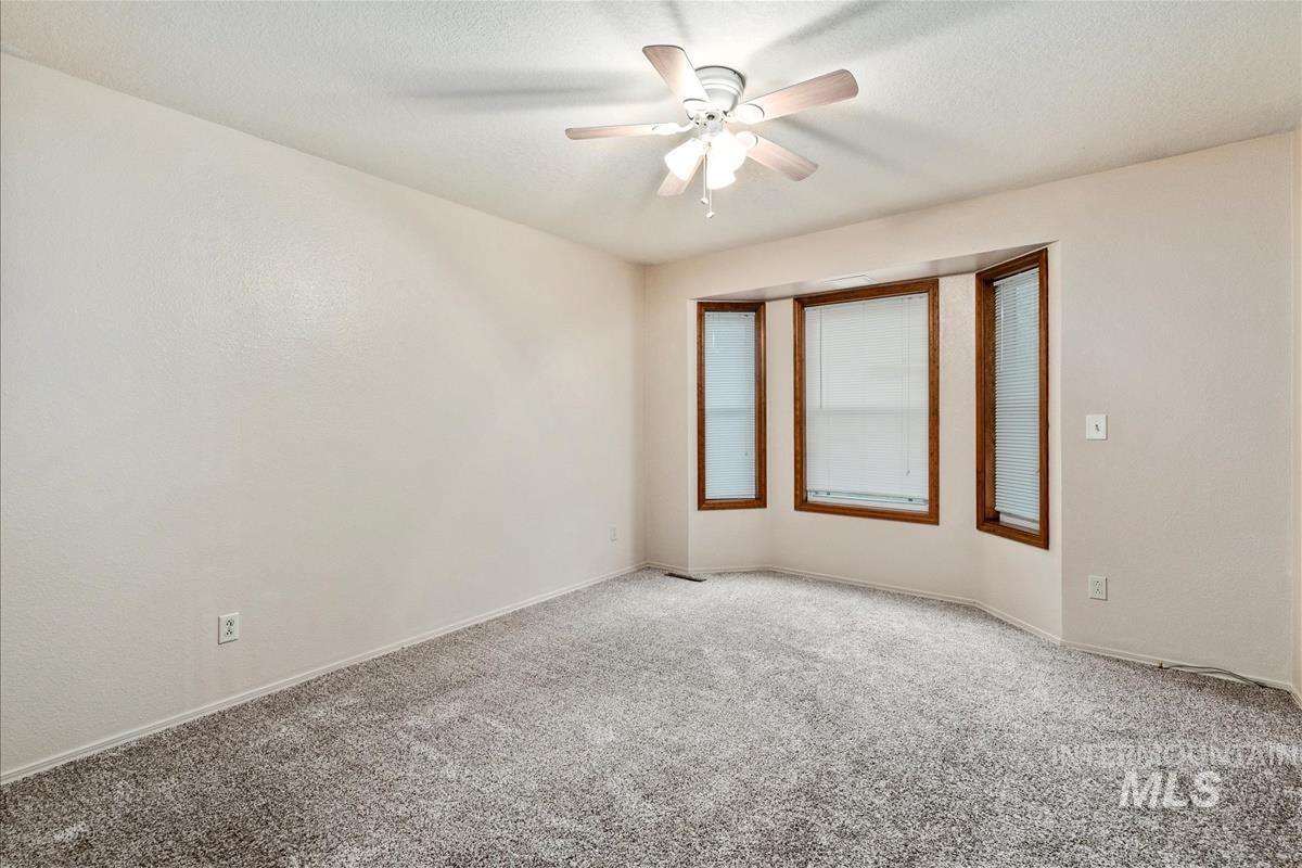 Carpeted empty room featuring ceiling fan and a textured ceiling