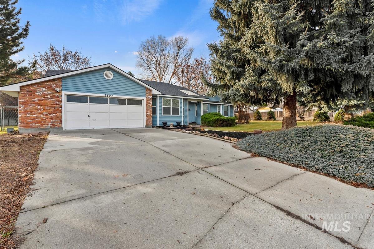 Single story home featuring concrete driveway, brick siding, a garage, and a front lawn