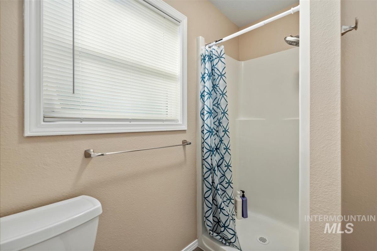 Full bath featuring a shower stall and a textured wall