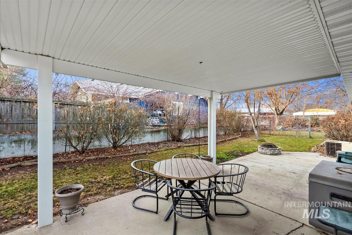 Fenced backyard featuring outdoor dining space, a patio, a fire pit, and a water view