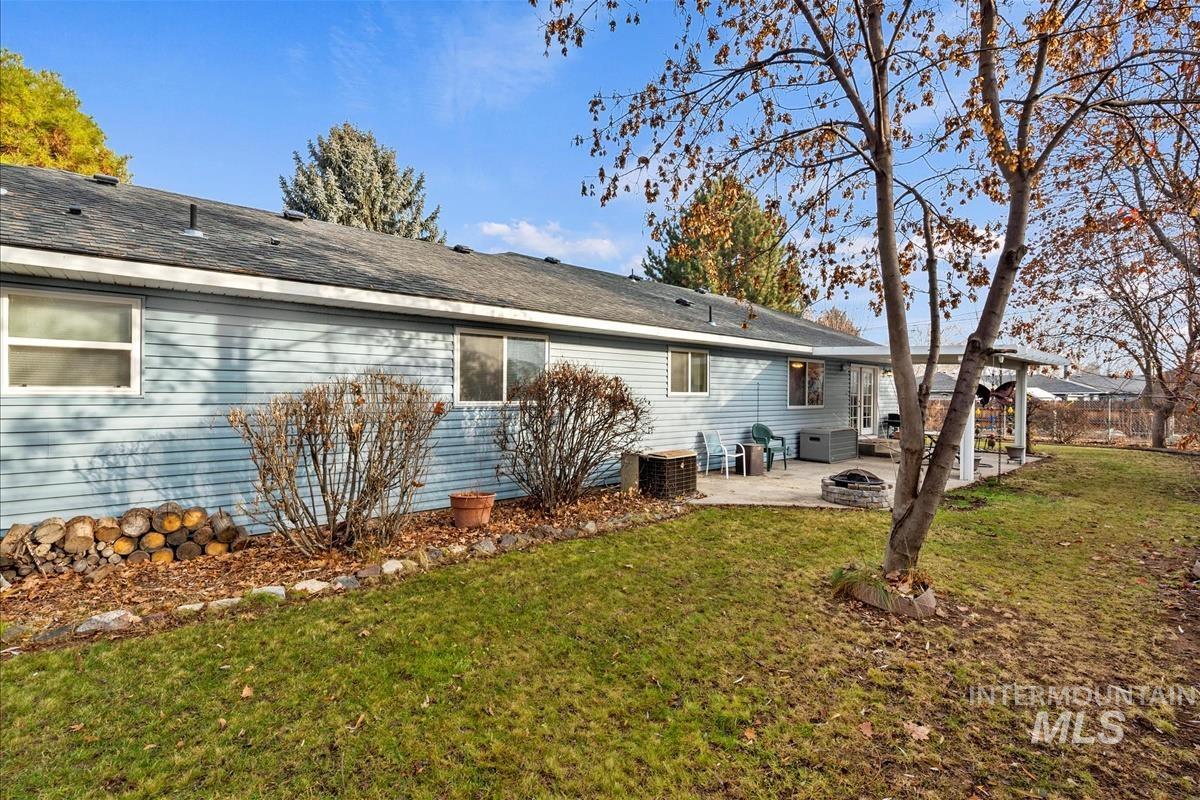 Back of property with a yard, a patio area, a fire pit, and a shingled roof