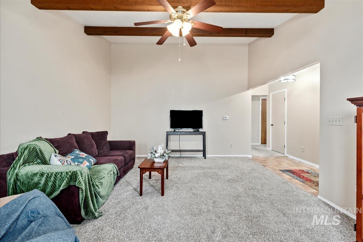 Carpeted living area featuring beam ceiling and ceiling fan