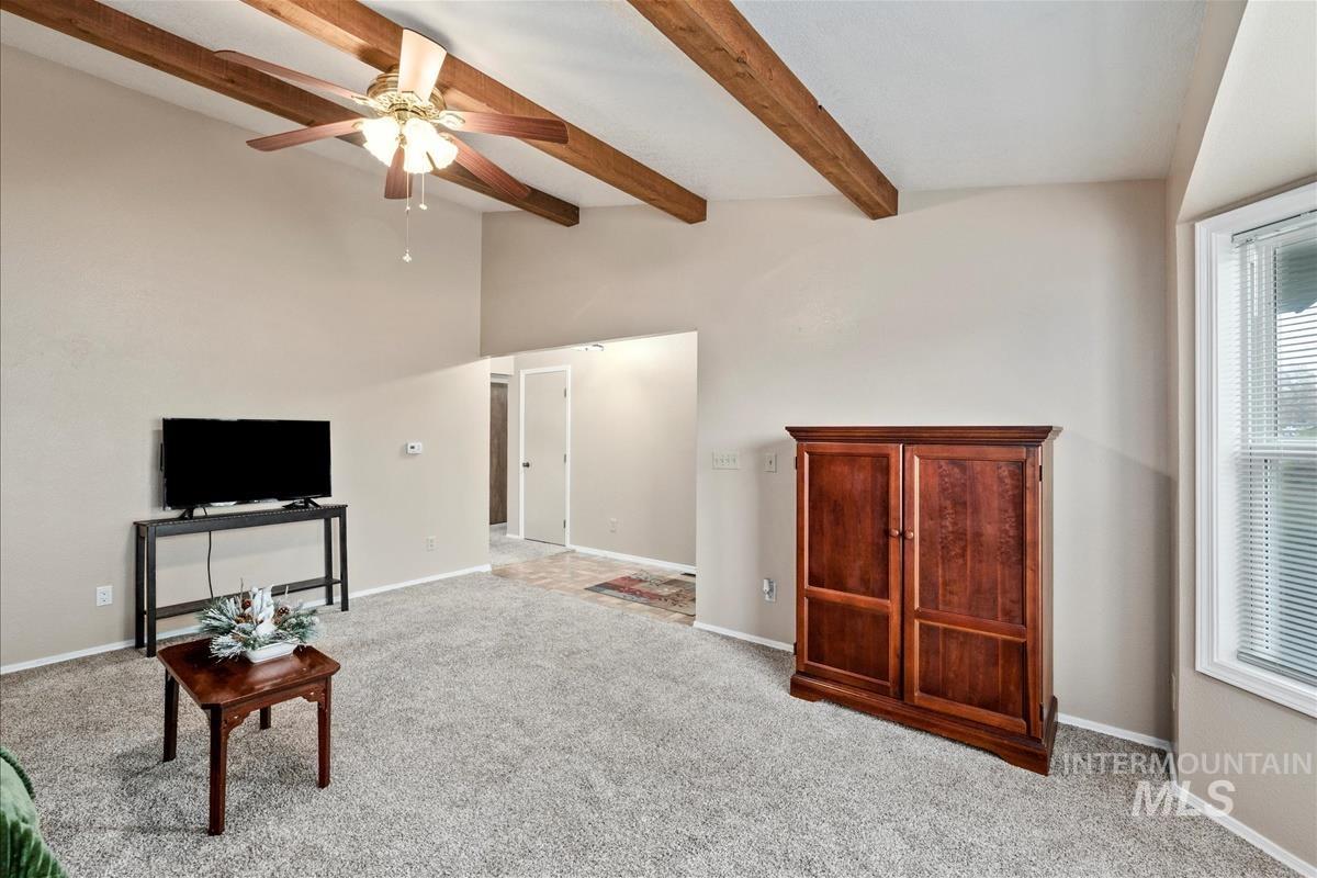 Living area with light colored carpet and a ceiling fan