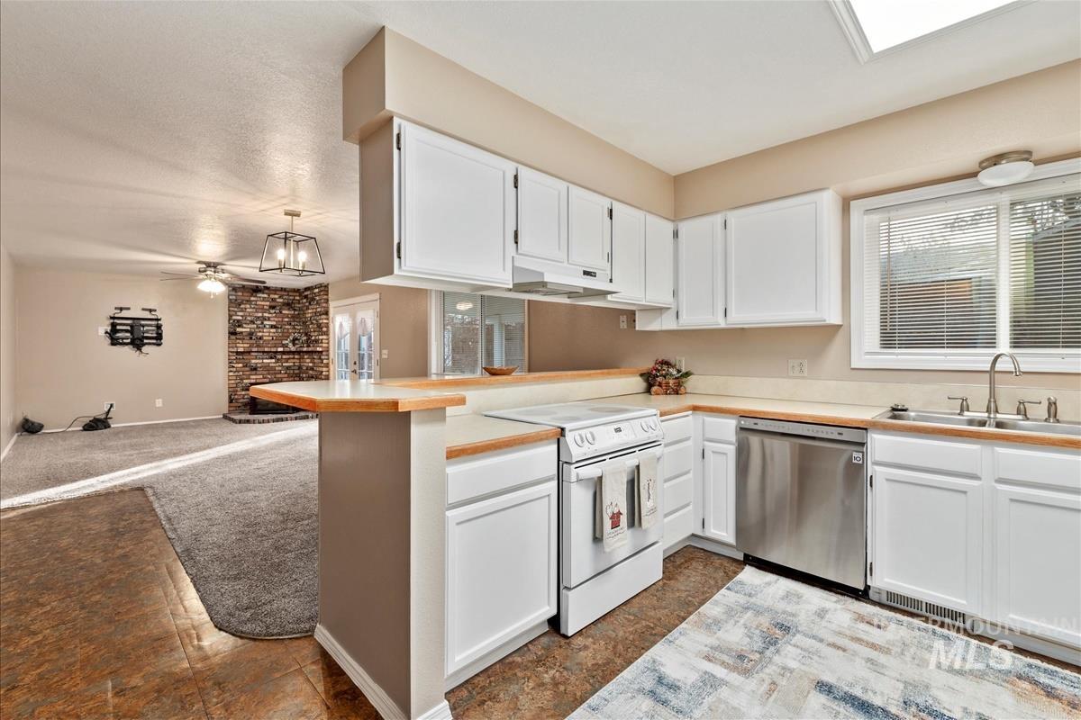 Kitchen featuring white cabinets, white electric range, light countertops, and dark carpet