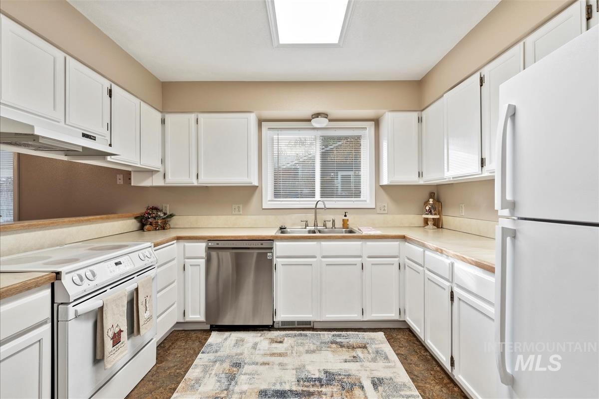 Kitchen with white appliances, light countertops, and white cabinets