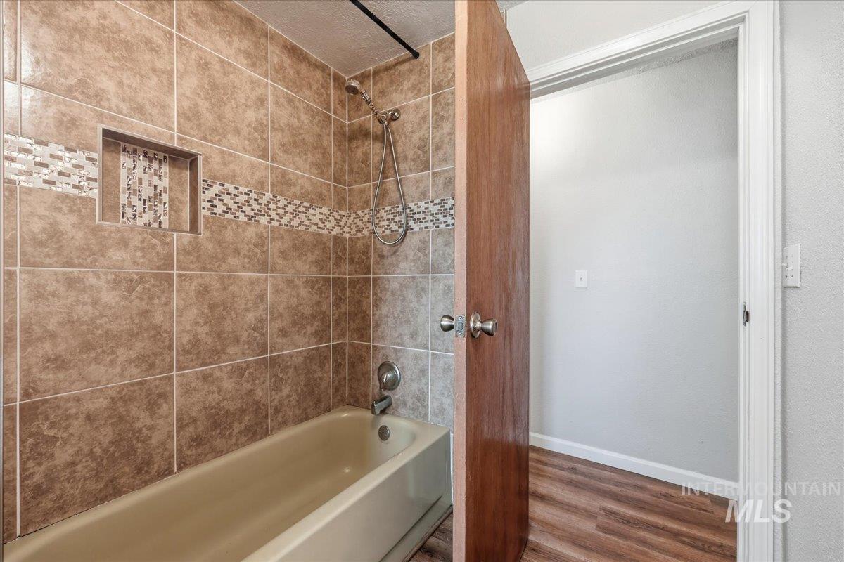 Full bathroom featuring wood finished floors and tub / shower combination