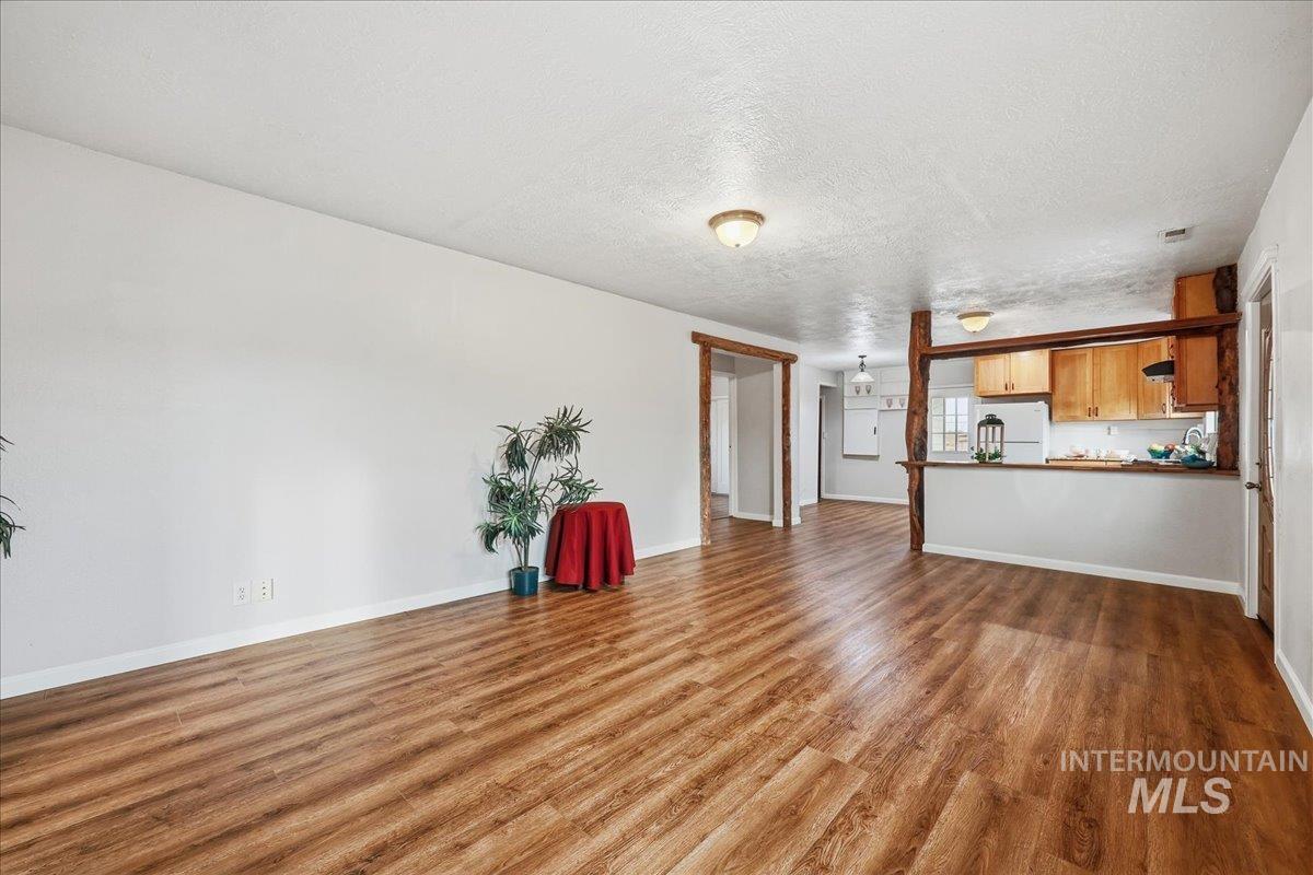 Unfurnished living room with a textured ceiling and dark wood finished floors