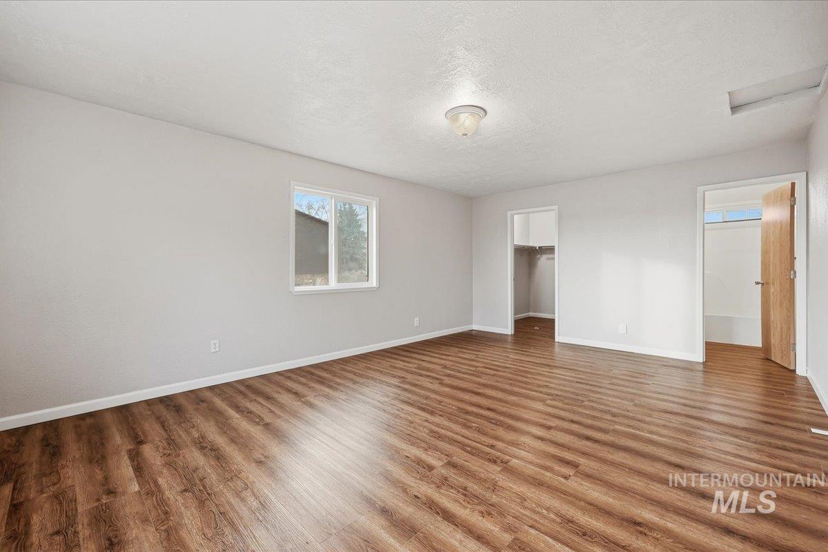 Unfurnished bedroom with a spacious closet, a textured ceiling, and wood finished floors