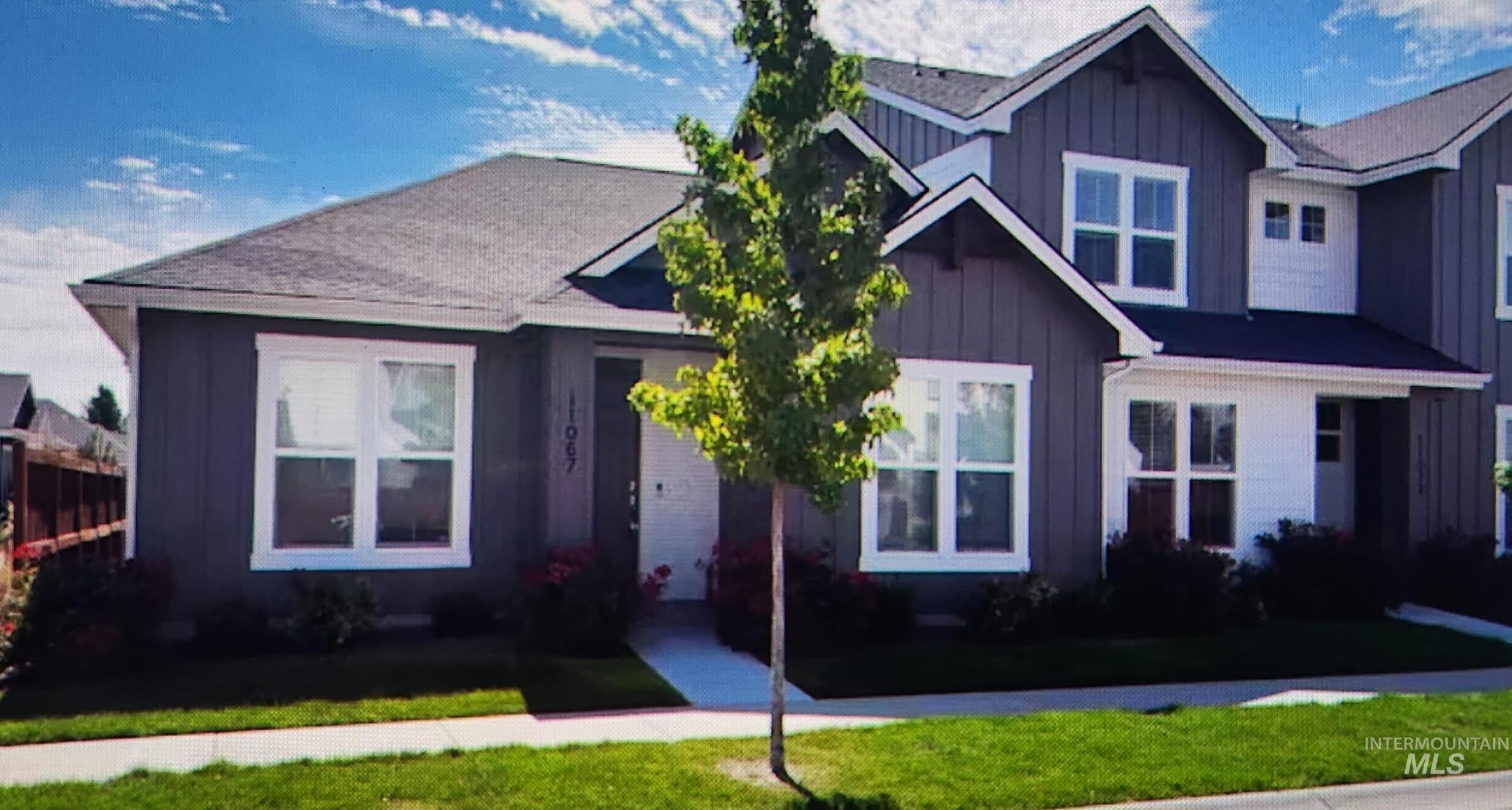 View of front of property with board and batten siding, a front yard, and roof with shingles