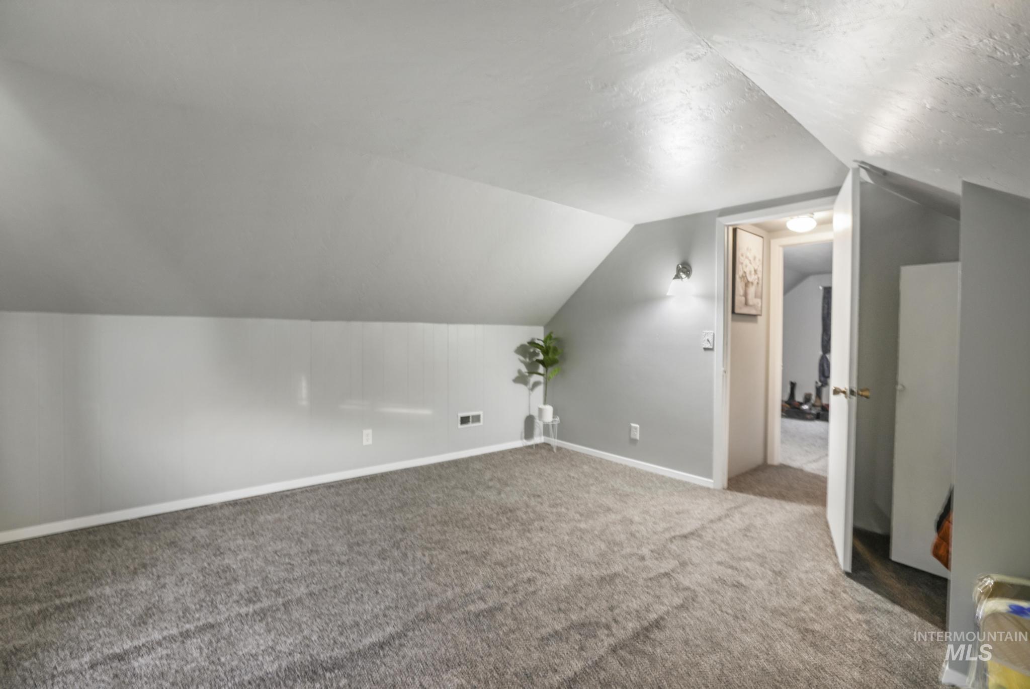 Additional living space with lofted ceiling and carpet and closet.