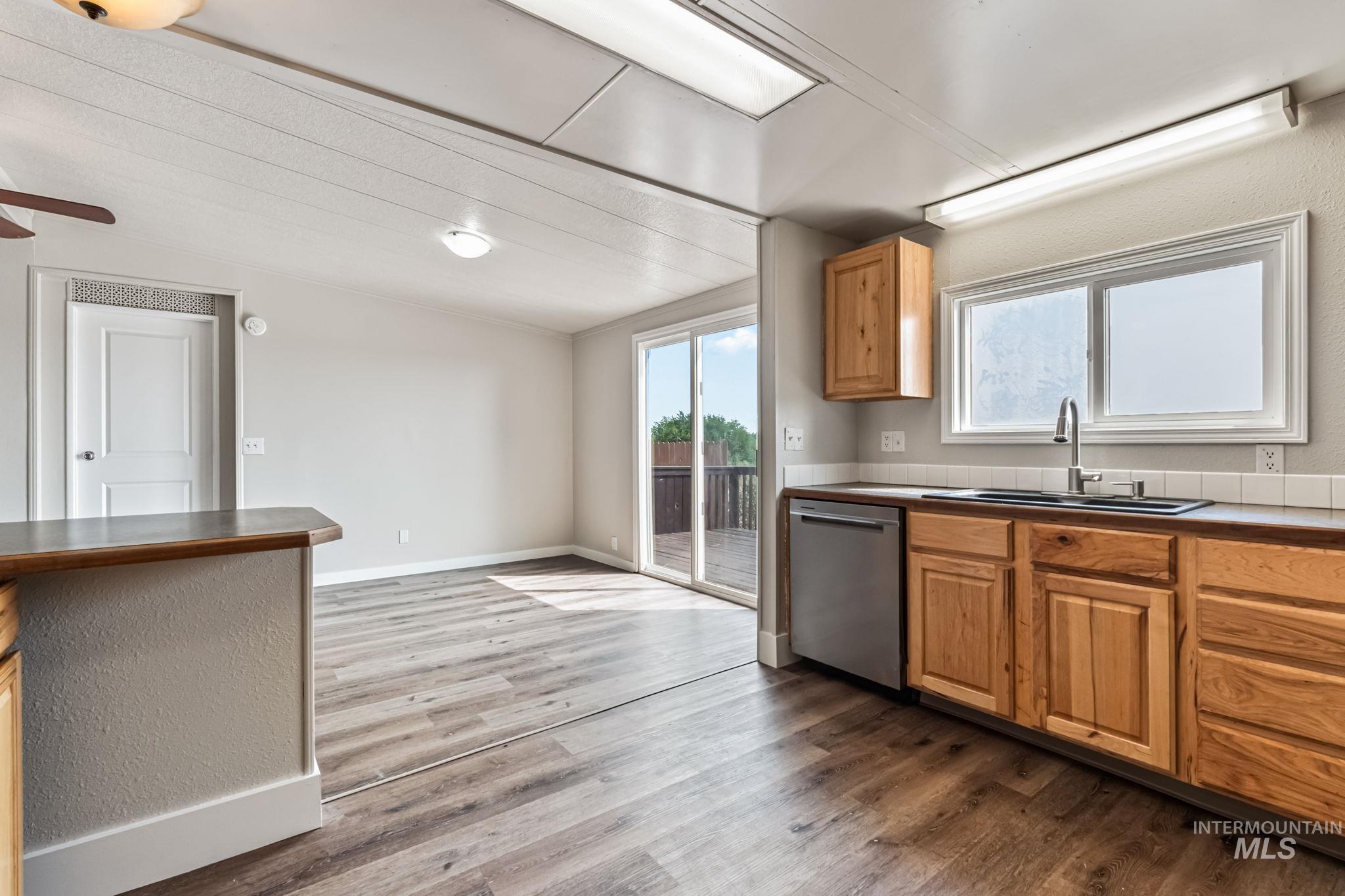 Kitchen featuring dishwasher, dark wood-type flooring, dark countertops, and brown cabinetry