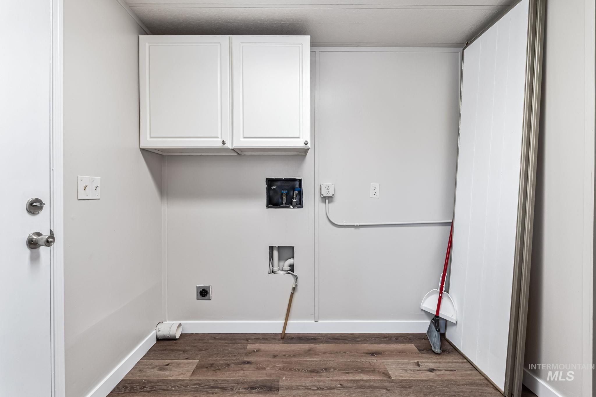 Washroom with hookup for a washing machine, dark wood finished floors, hookup for an electric dryer, and cabinet space