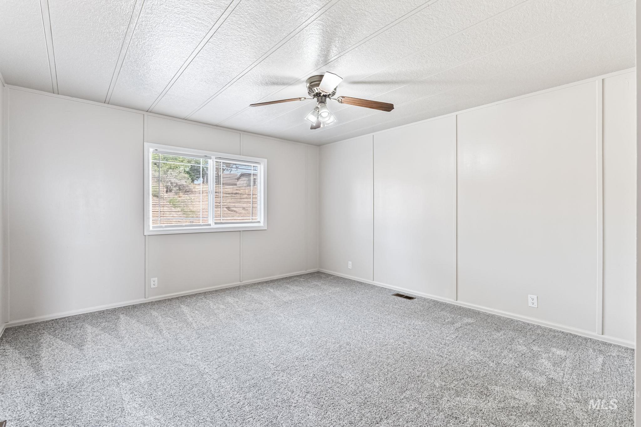 Spare room with carpet floors, a textured ceiling, and ceiling fan