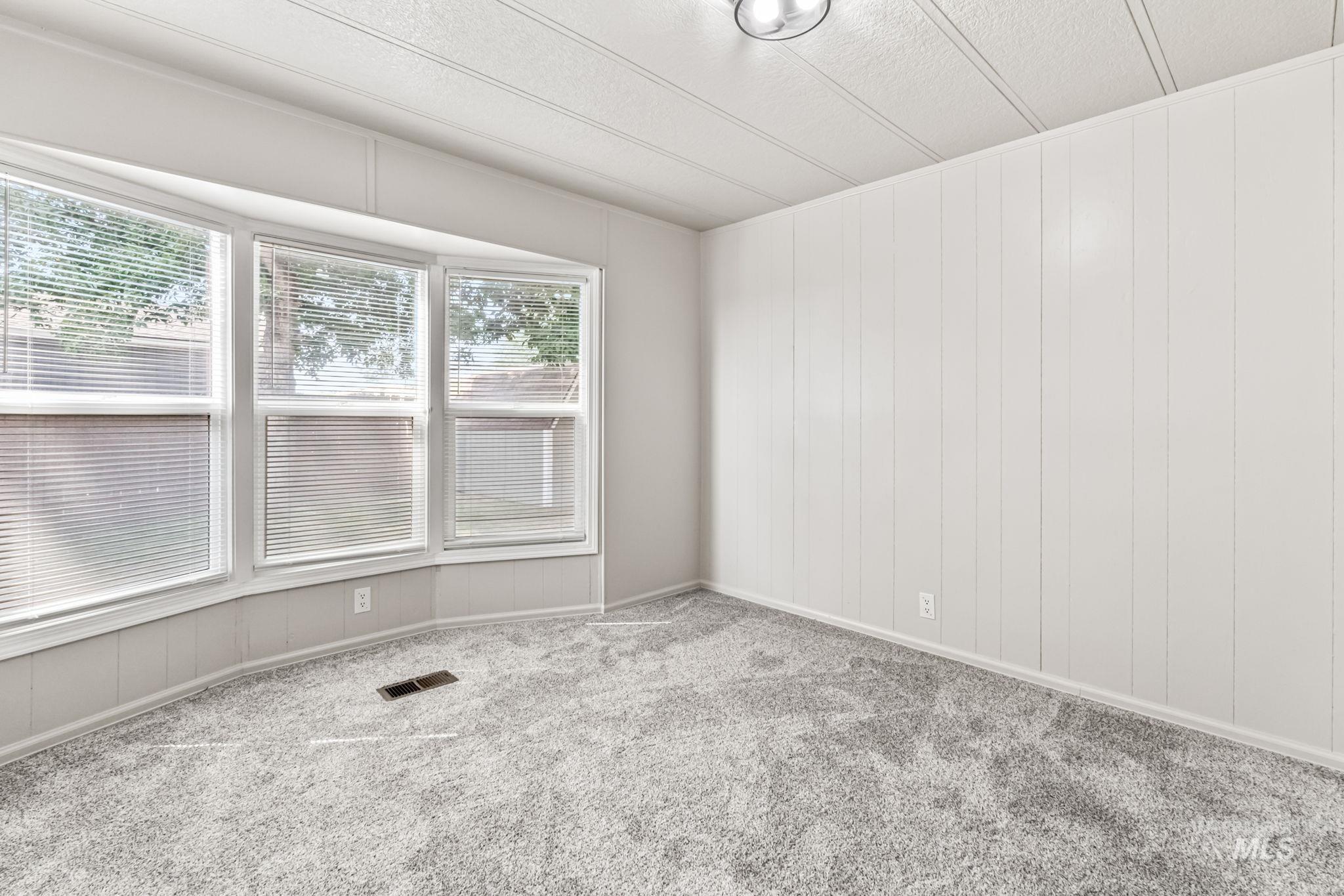 Carpeted empty room featuring wooden walls