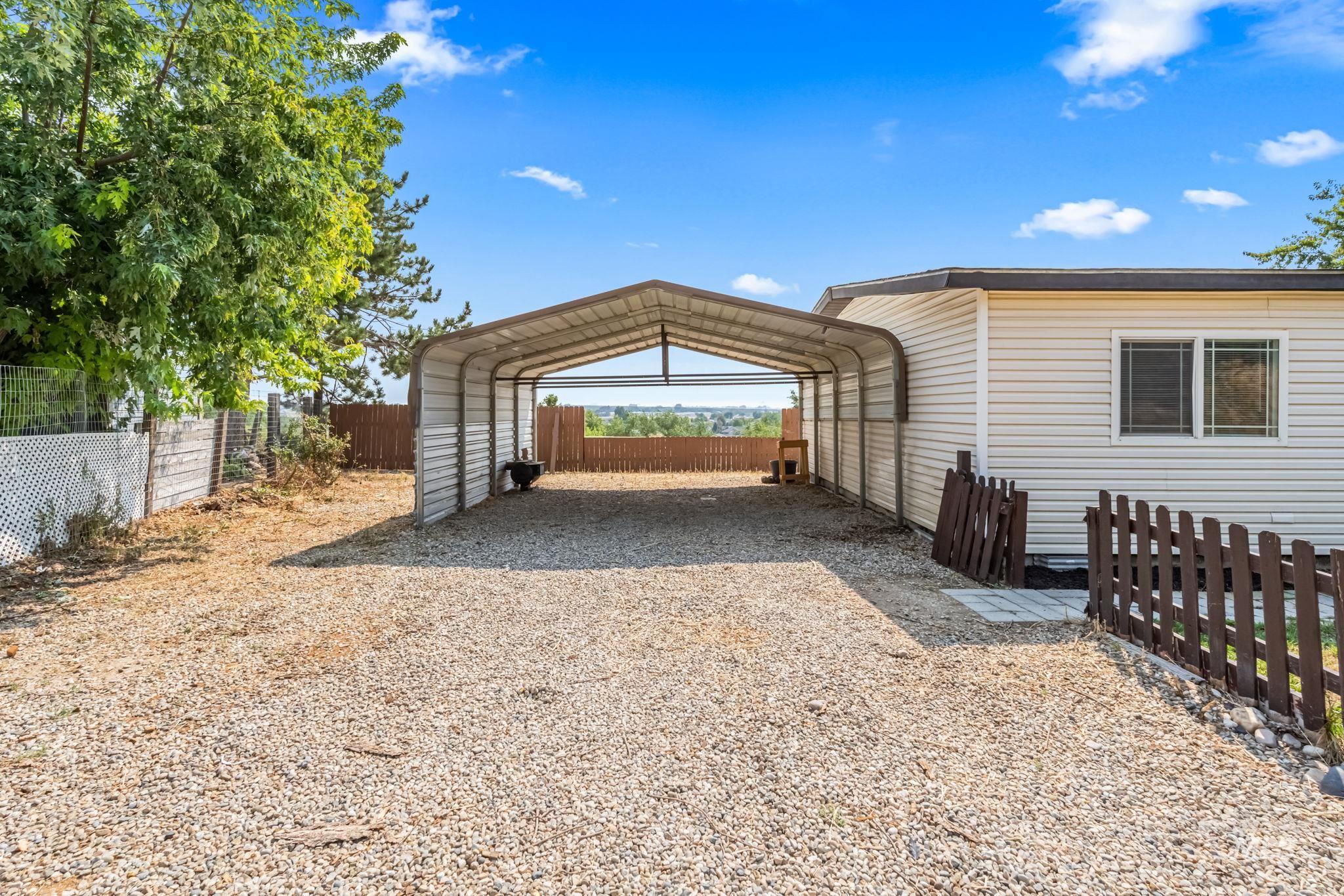 View of parking / parking lot featuring gravel driveway and a carport
