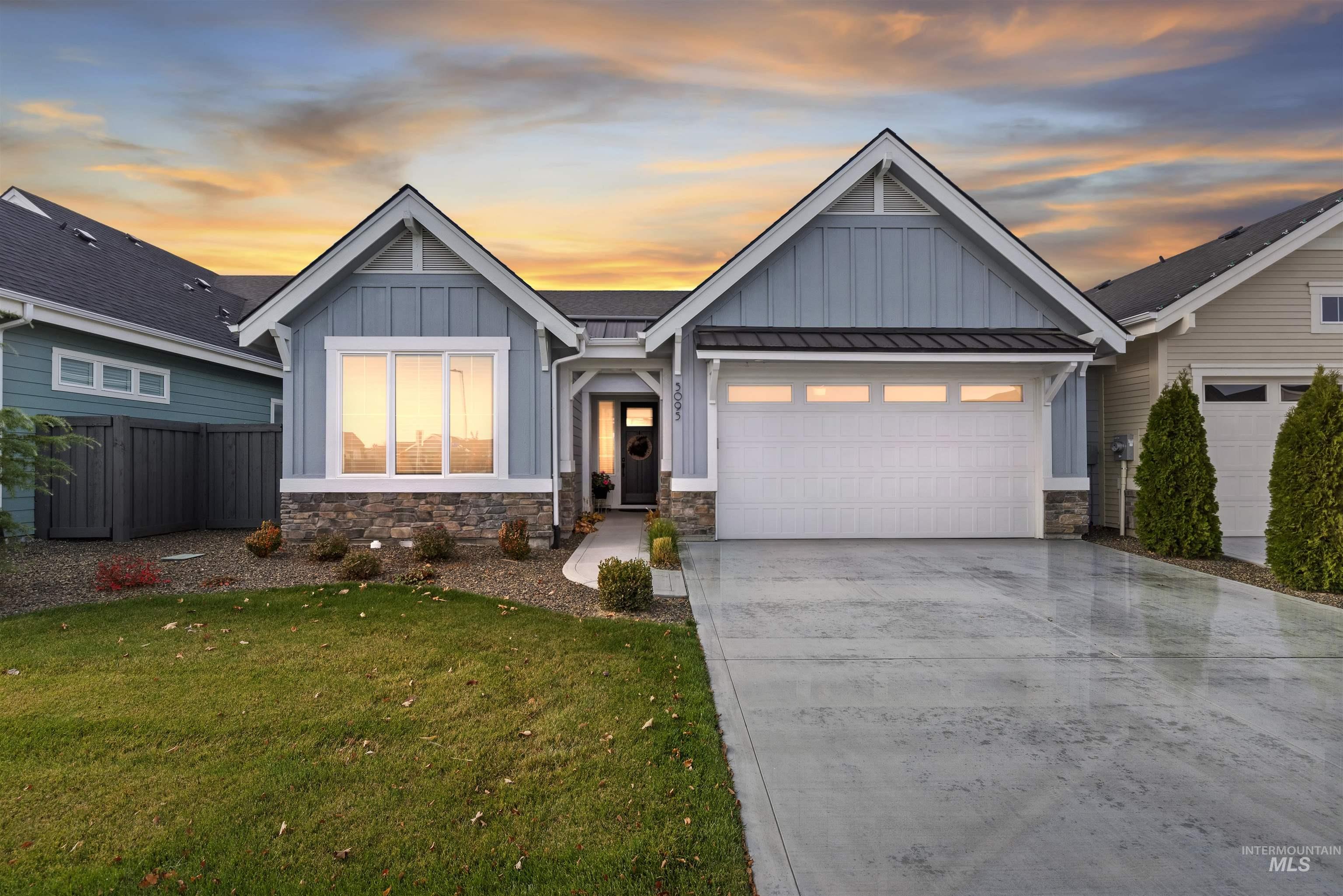 Craftsman inspired home featuring board and batten siding, concrete driveway, and stone siding
