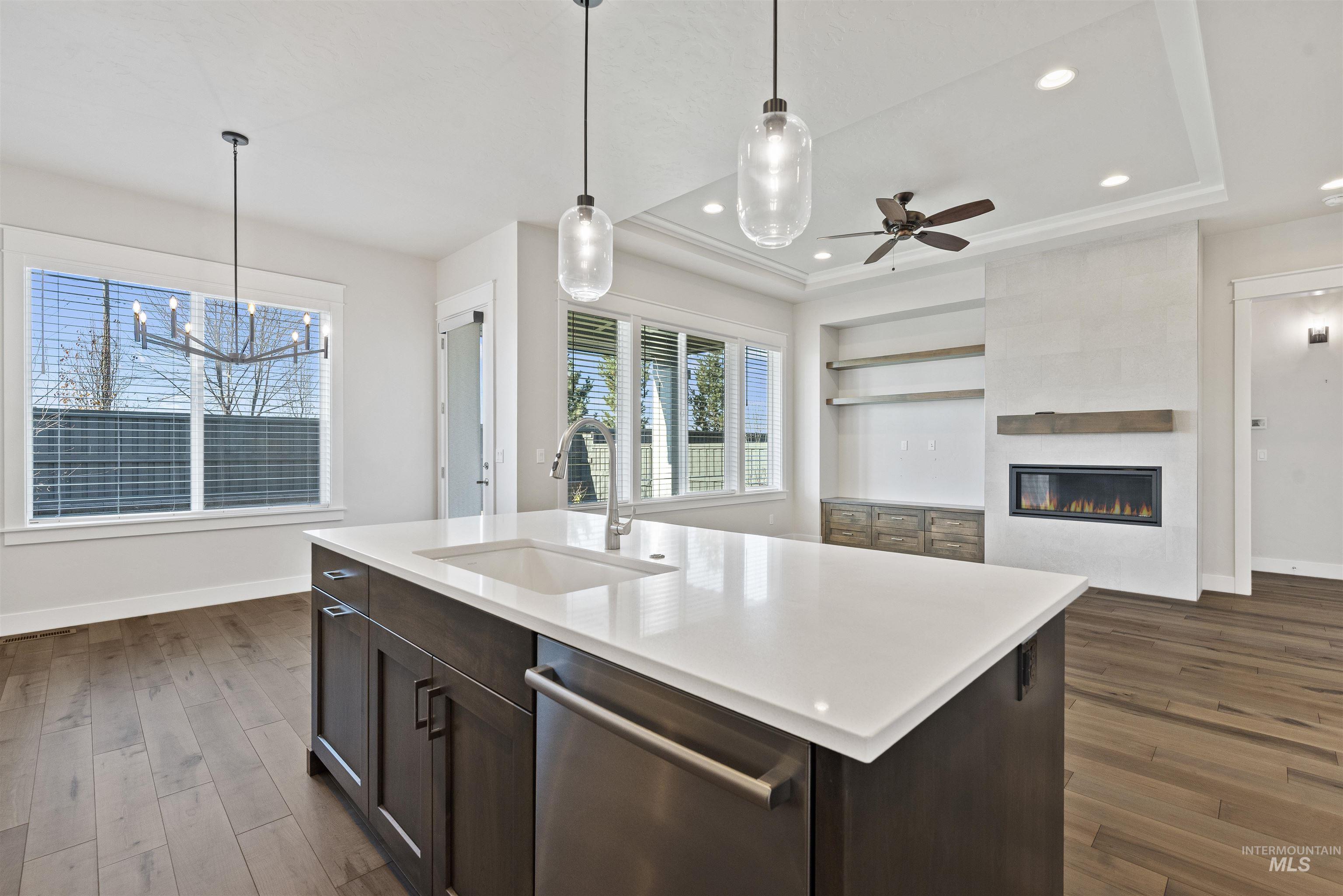 Kitchen with dark brown cabinets, dishwasher, open floor plan, dark wood finished floors, and hanging light fixtures