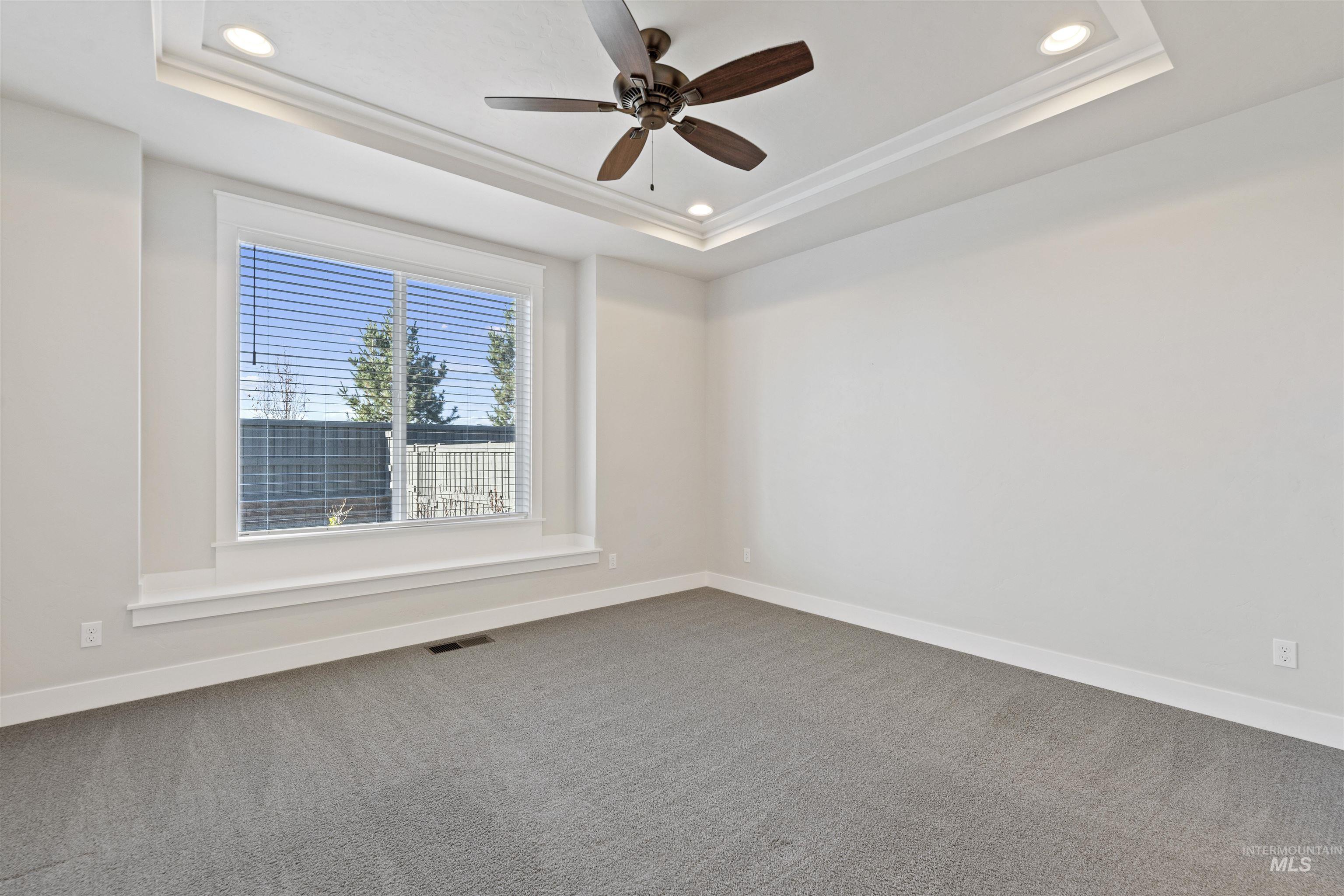 Spare room featuring carpet flooring, ceiling fan, recessed lighting, and a raised ceiling