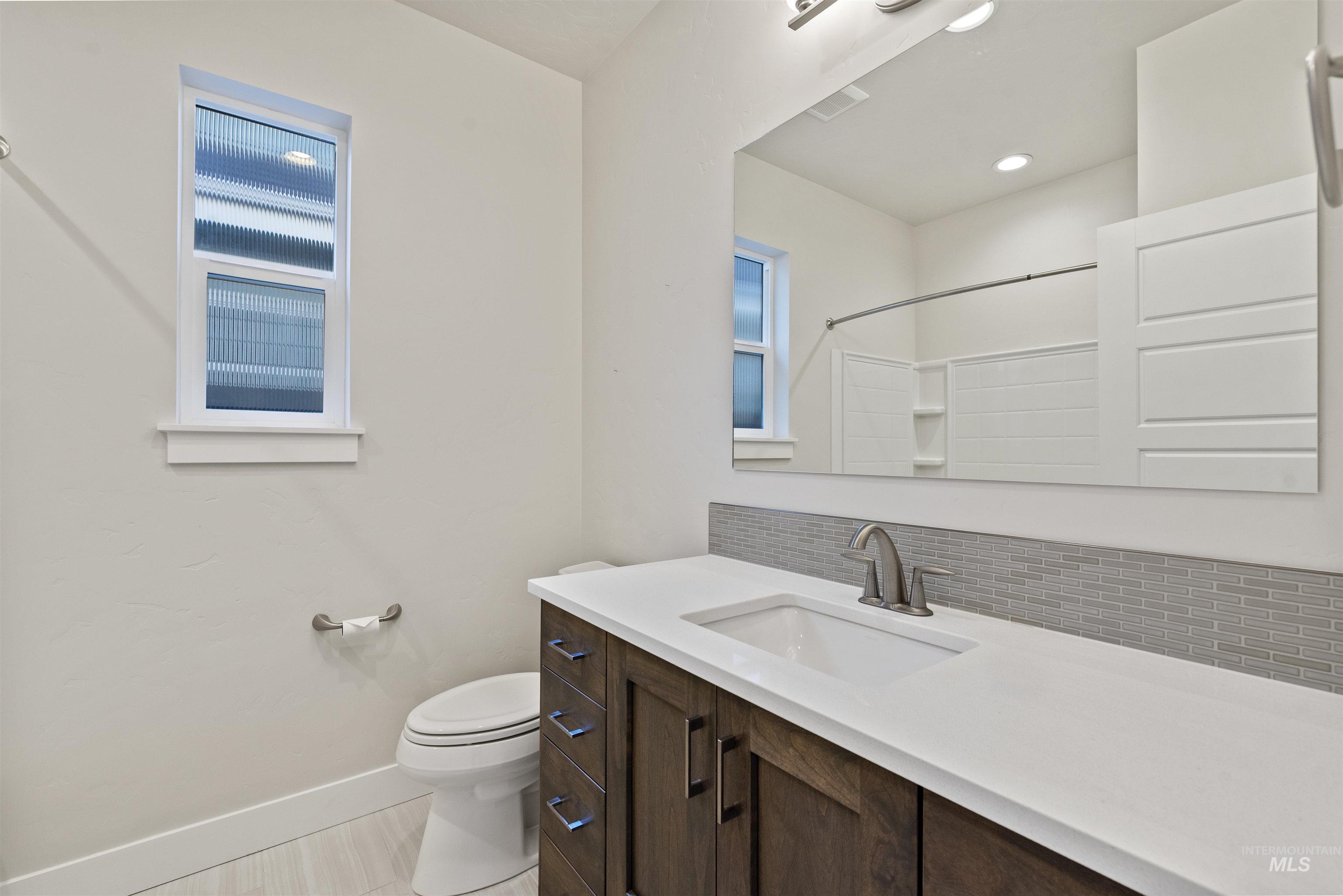 Bathroom featuring decorative backsplash, vanity, a shower, and recessed lighting