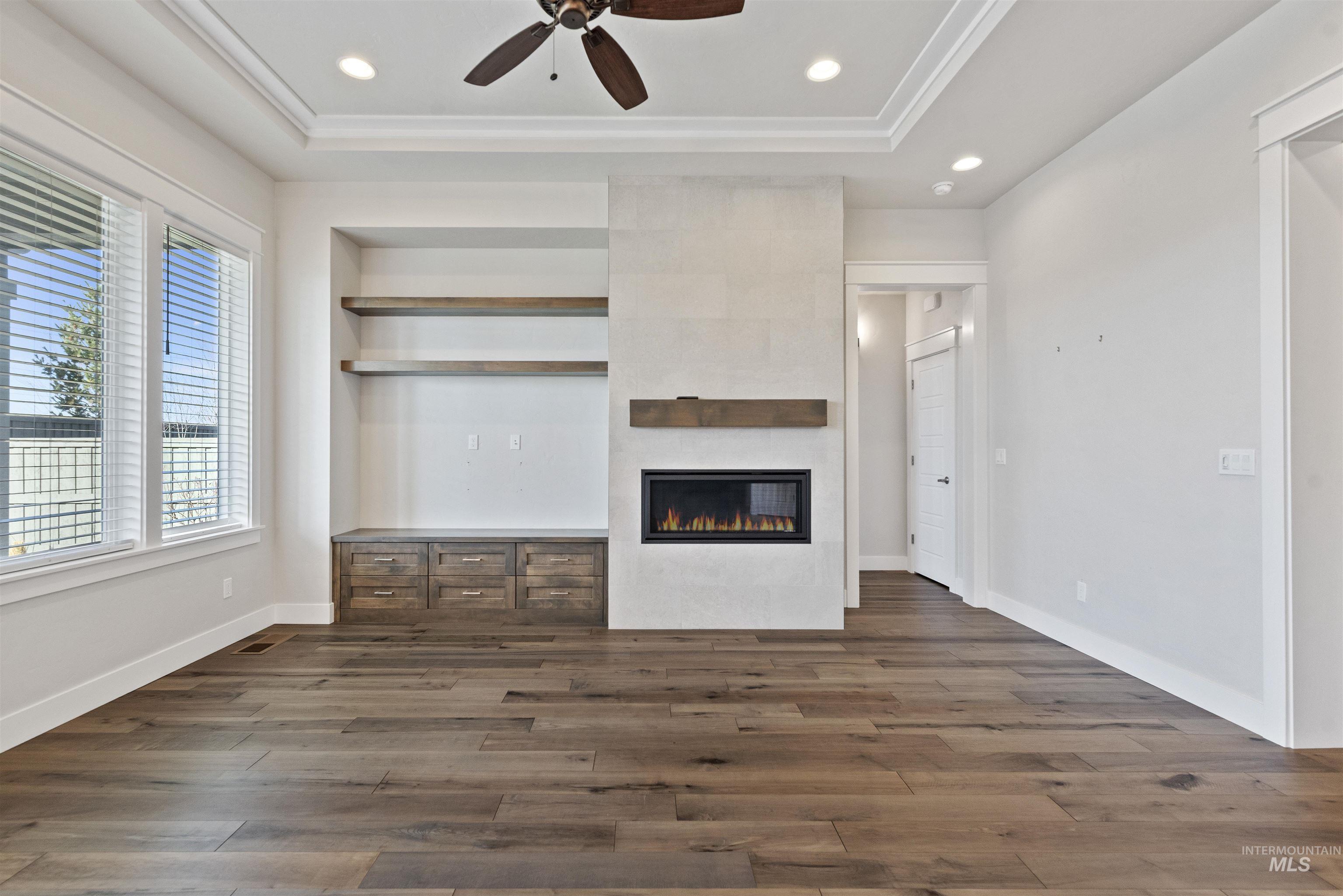 Unfurnished living room with a tile fireplace, dark wood-type flooring, recessed lighting, and a ceiling fan