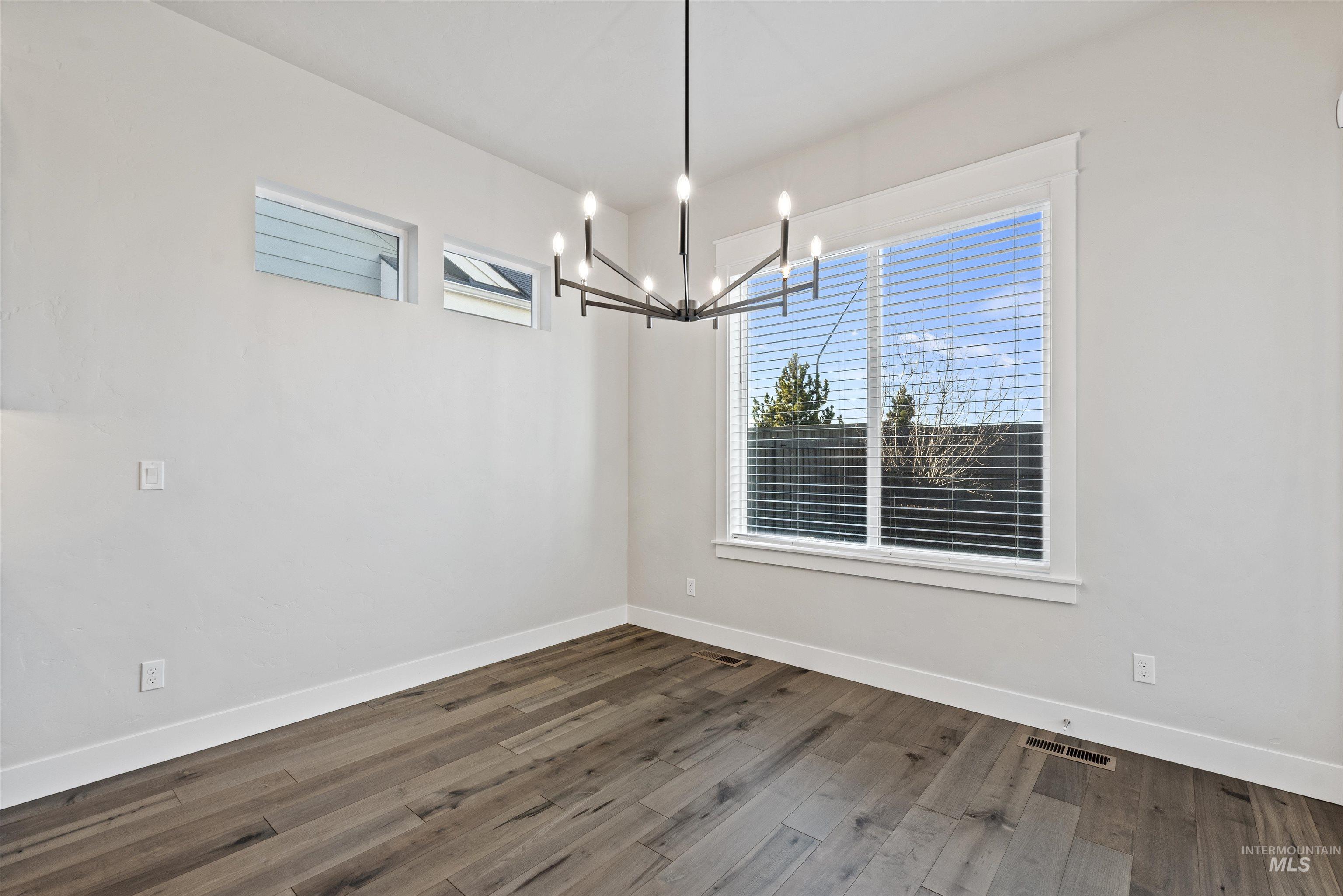 Unfurnished dining area with dark wood-style flooring and a chandelier