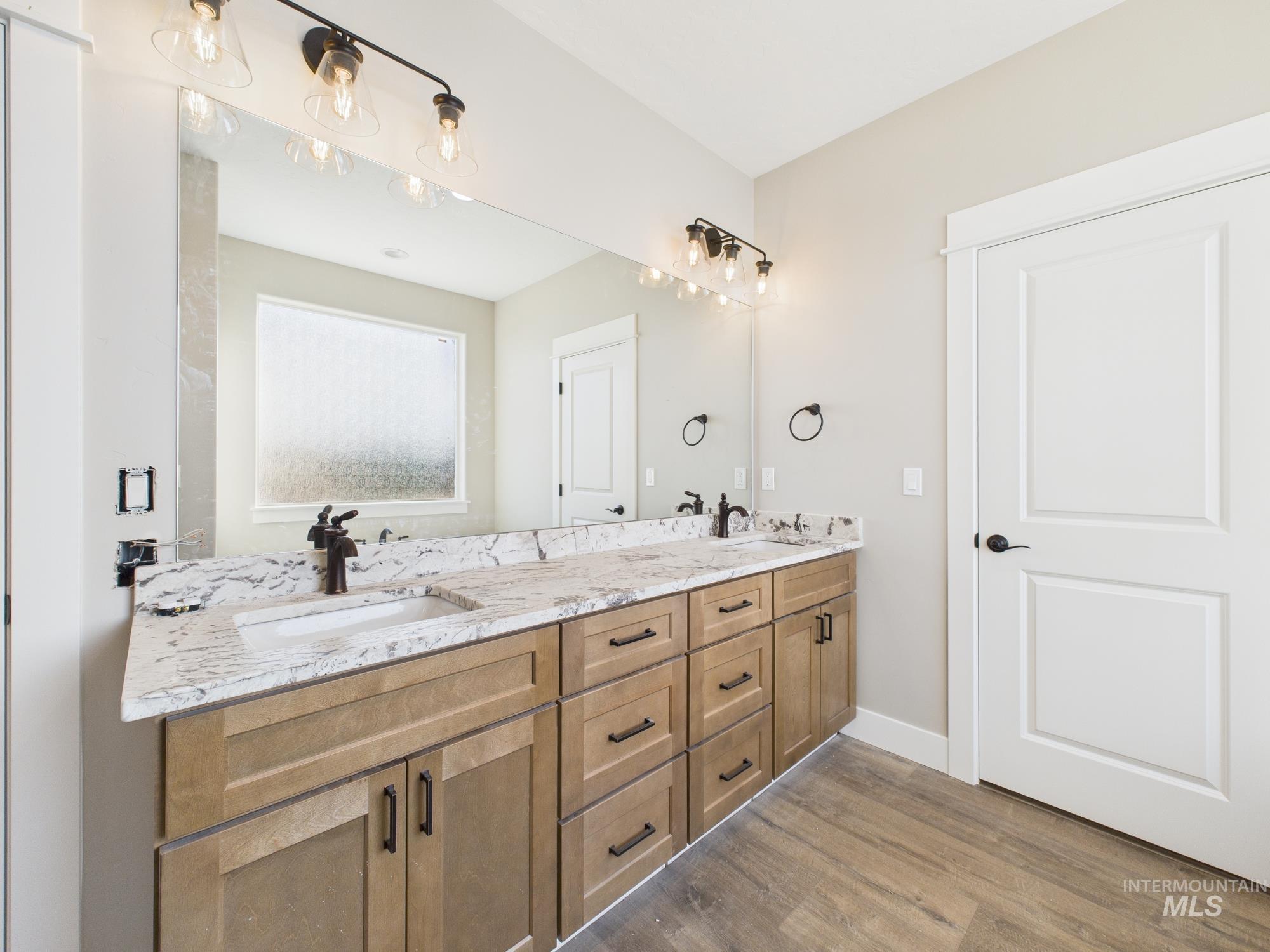 Bathroom with double vanity and light wood-type flooring