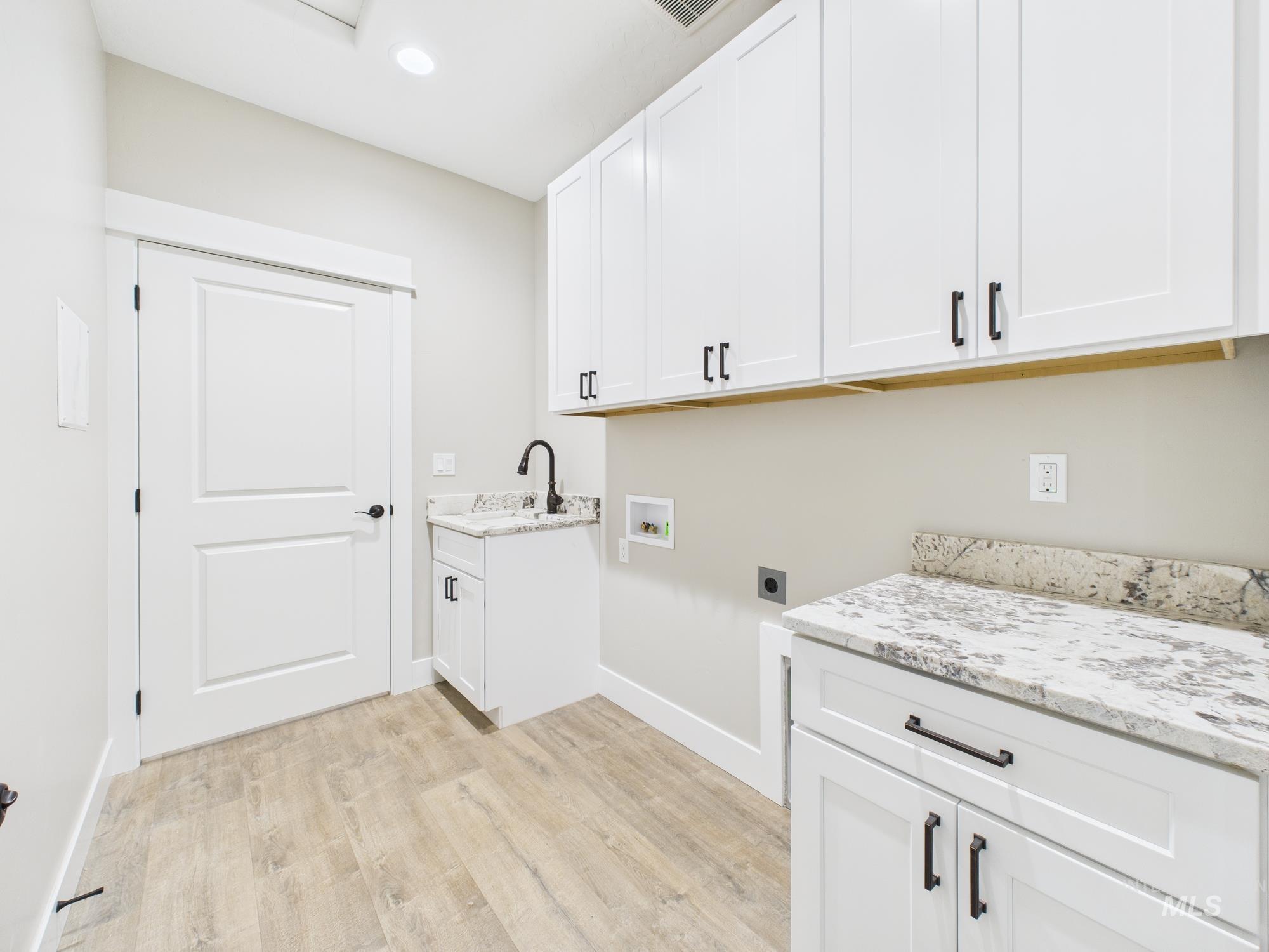 Washroom featuring cabinet space, hookup for a washing machine, hookup for an electric dryer, and light wood-type flooring