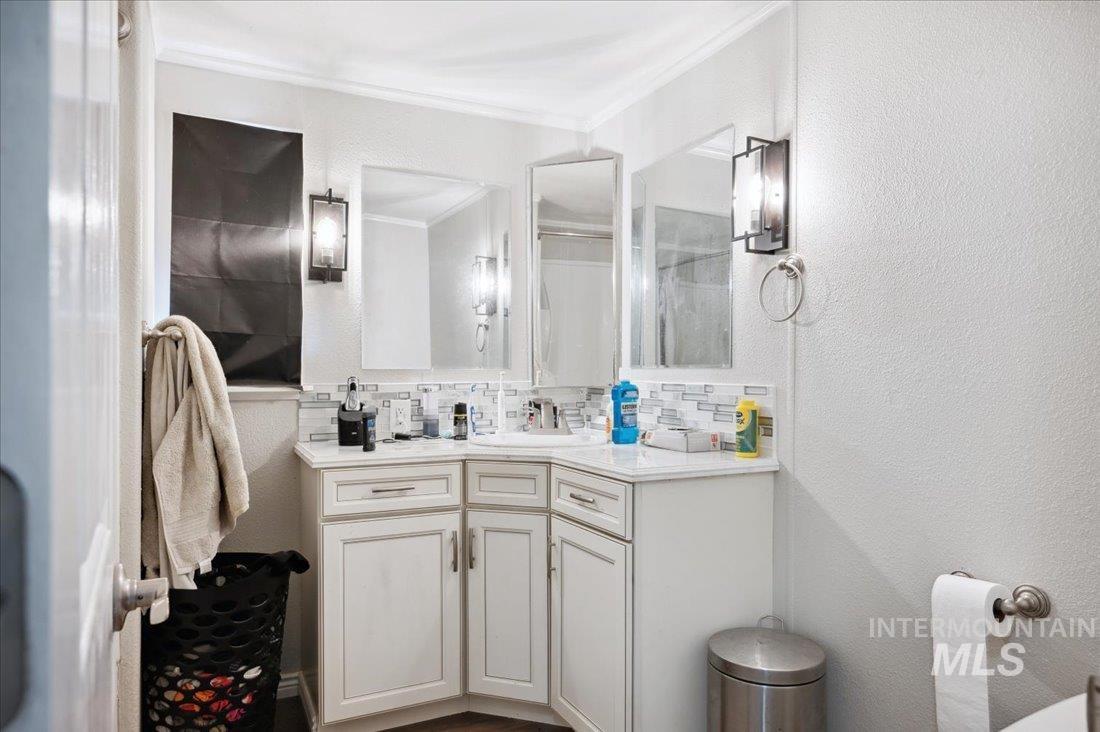 Bathroom with crown molding, vanity, and decorative backsplash