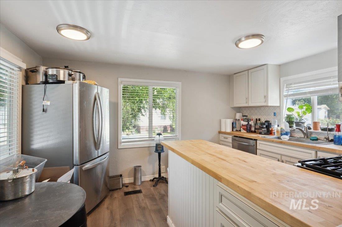 Kitchen featuring butcher block counters, stainless steel appliances, wood finished floors, and plenty of natural light