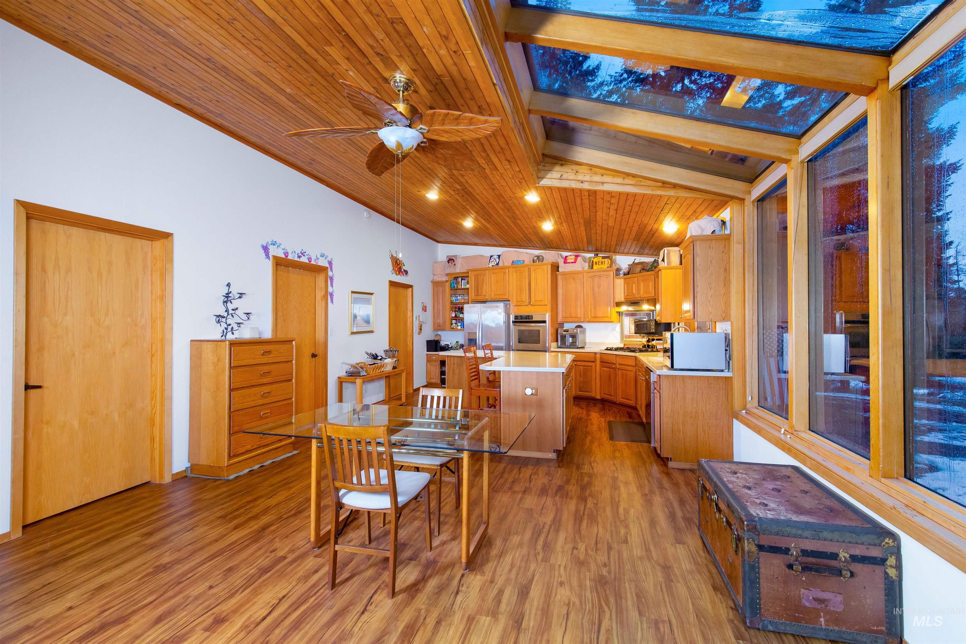 Dining room with wood ceiling, dark wood-style floors, ceiling fan, and lofted ceiling with vaulted glass window