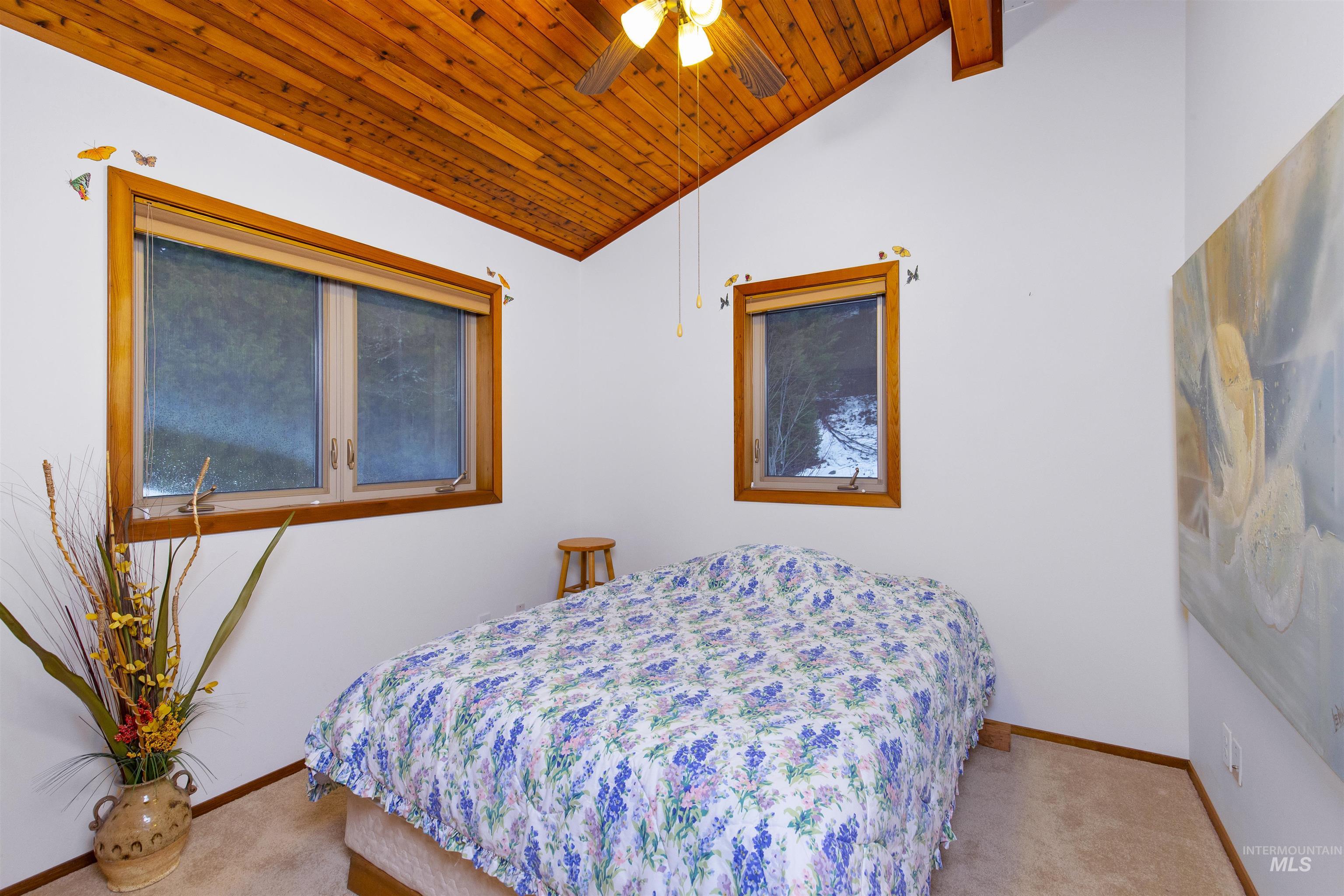 Bedroom in loft featuring vaulted ceiling, light carpet, wooden ceiling, and ceiling fan