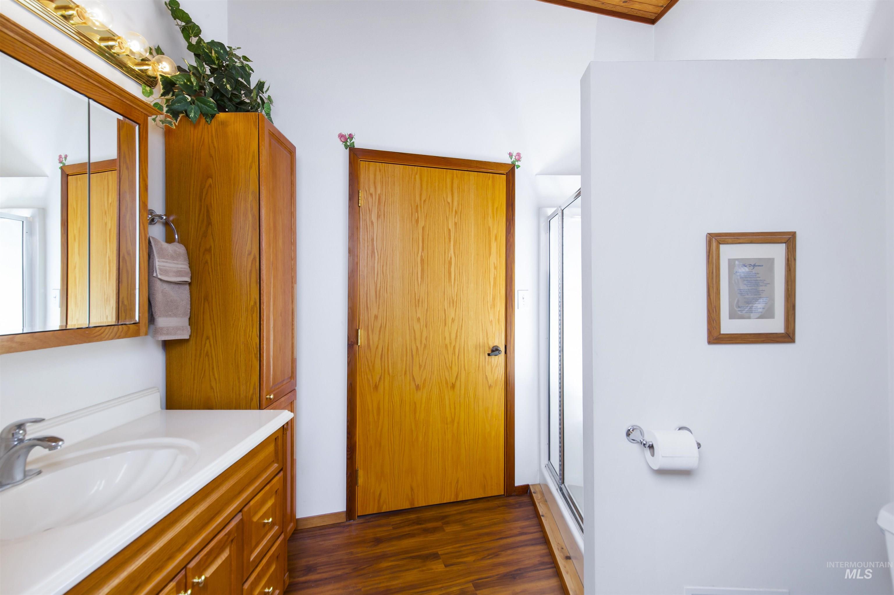 Full bathroom in loft with vanity, a shower stall, and dark wood-style floors