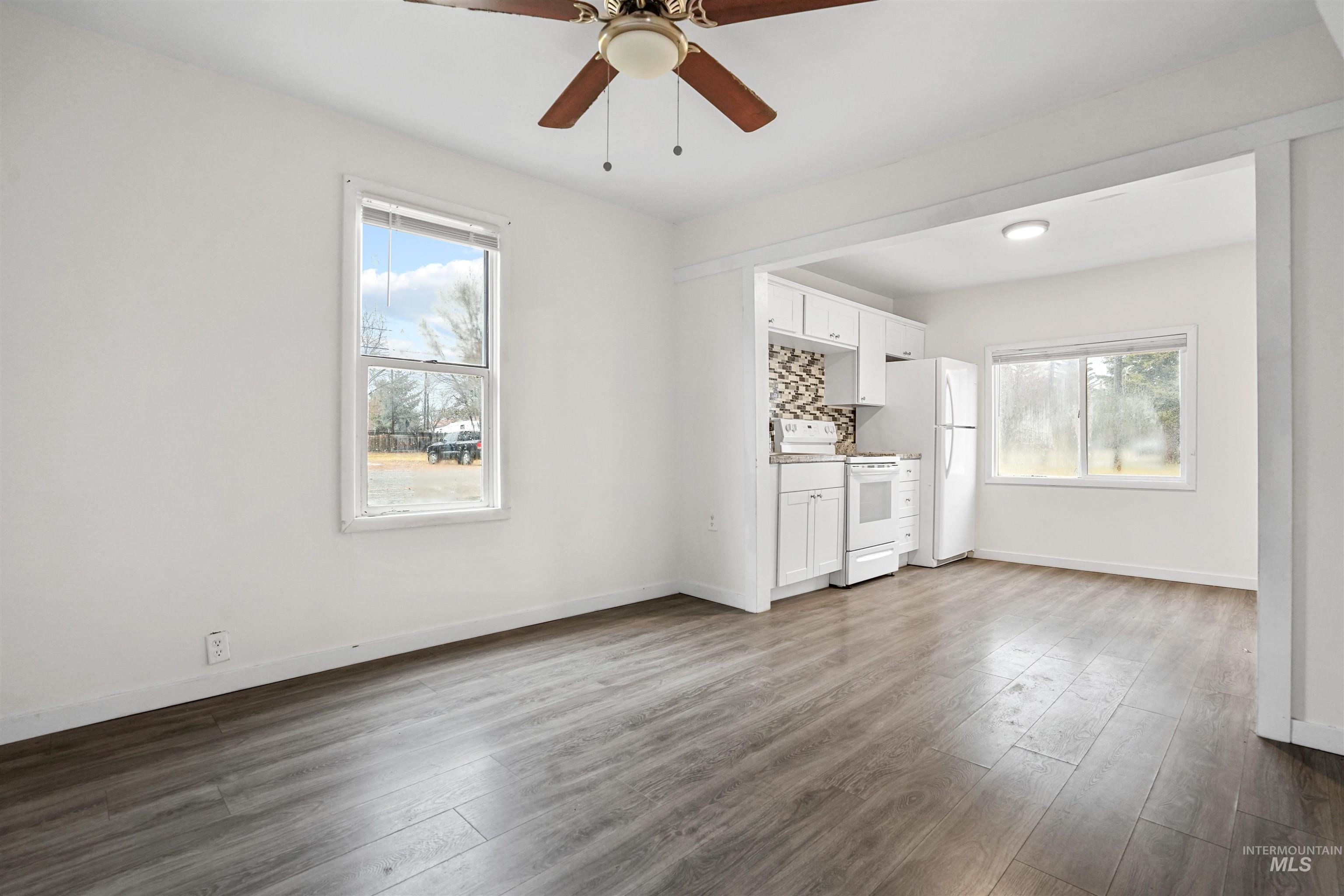 Unfurnished living room with dark wood finished floors, healthy amount of natural light, and a ceiling fan