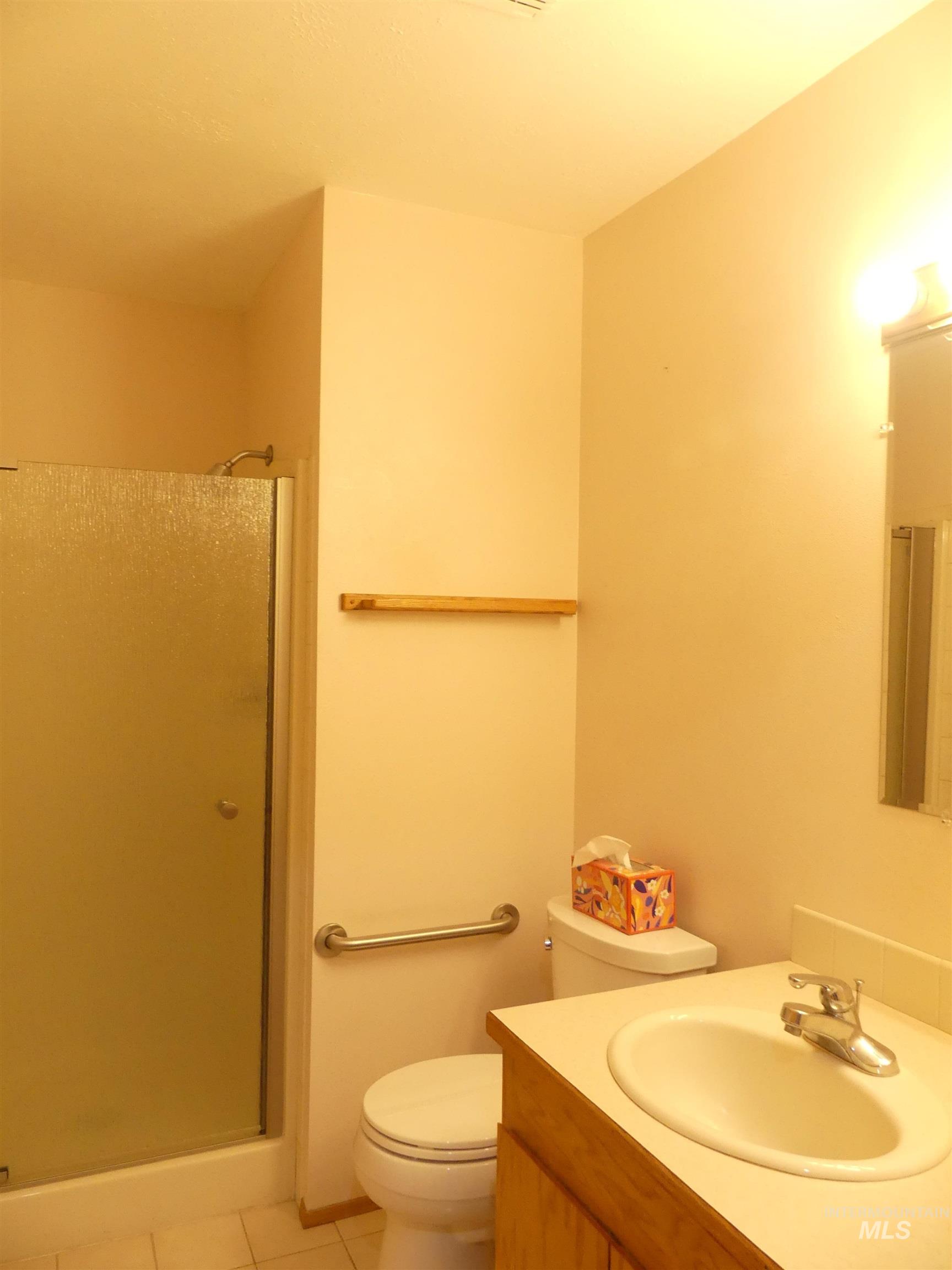 Full bath with vanity, light tile patterned floors, and a shower stall