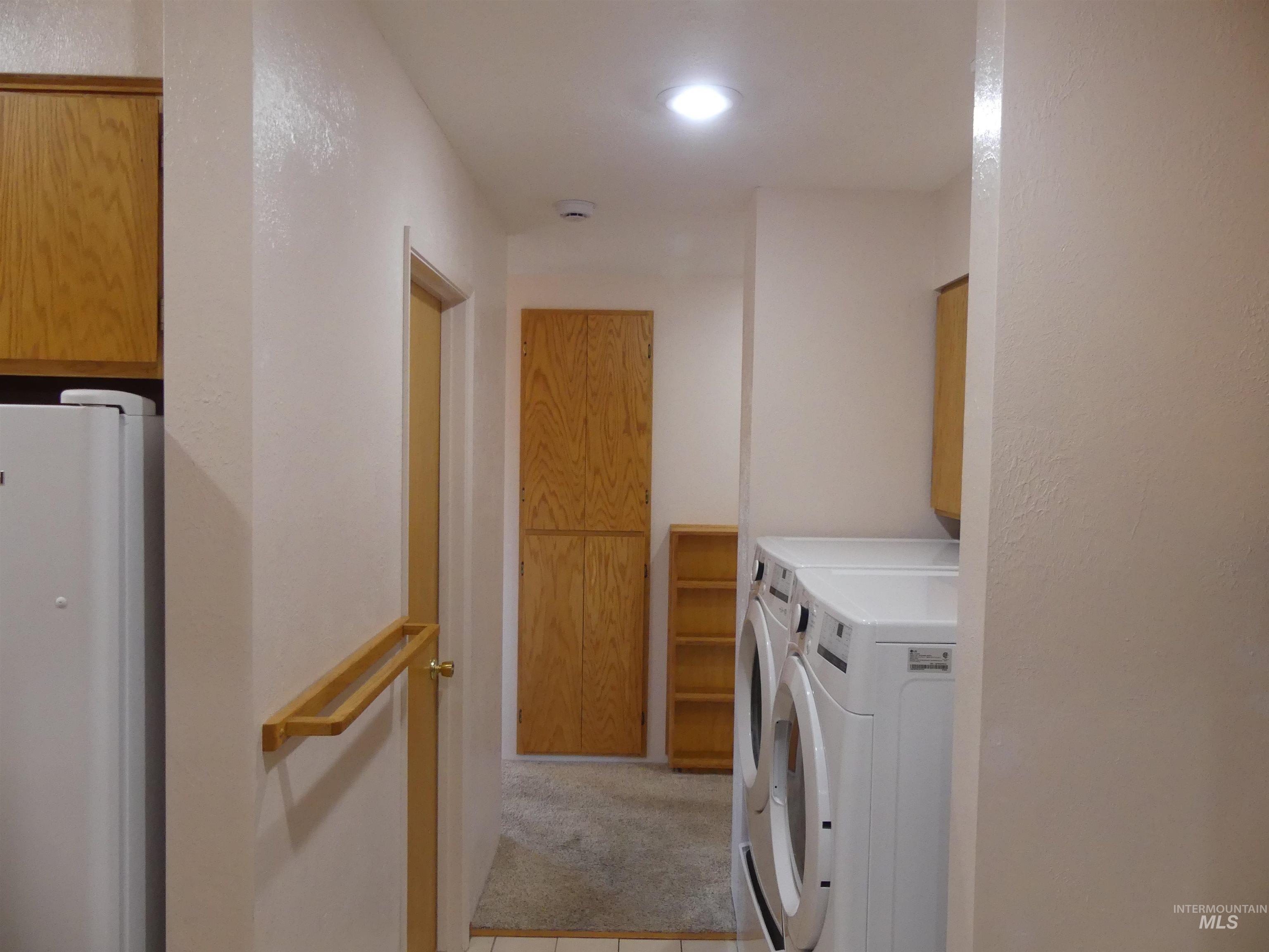 Laundry room featuring washer and clothes dryer, cabinet space, light colored carpet, and light tile patterned flooring