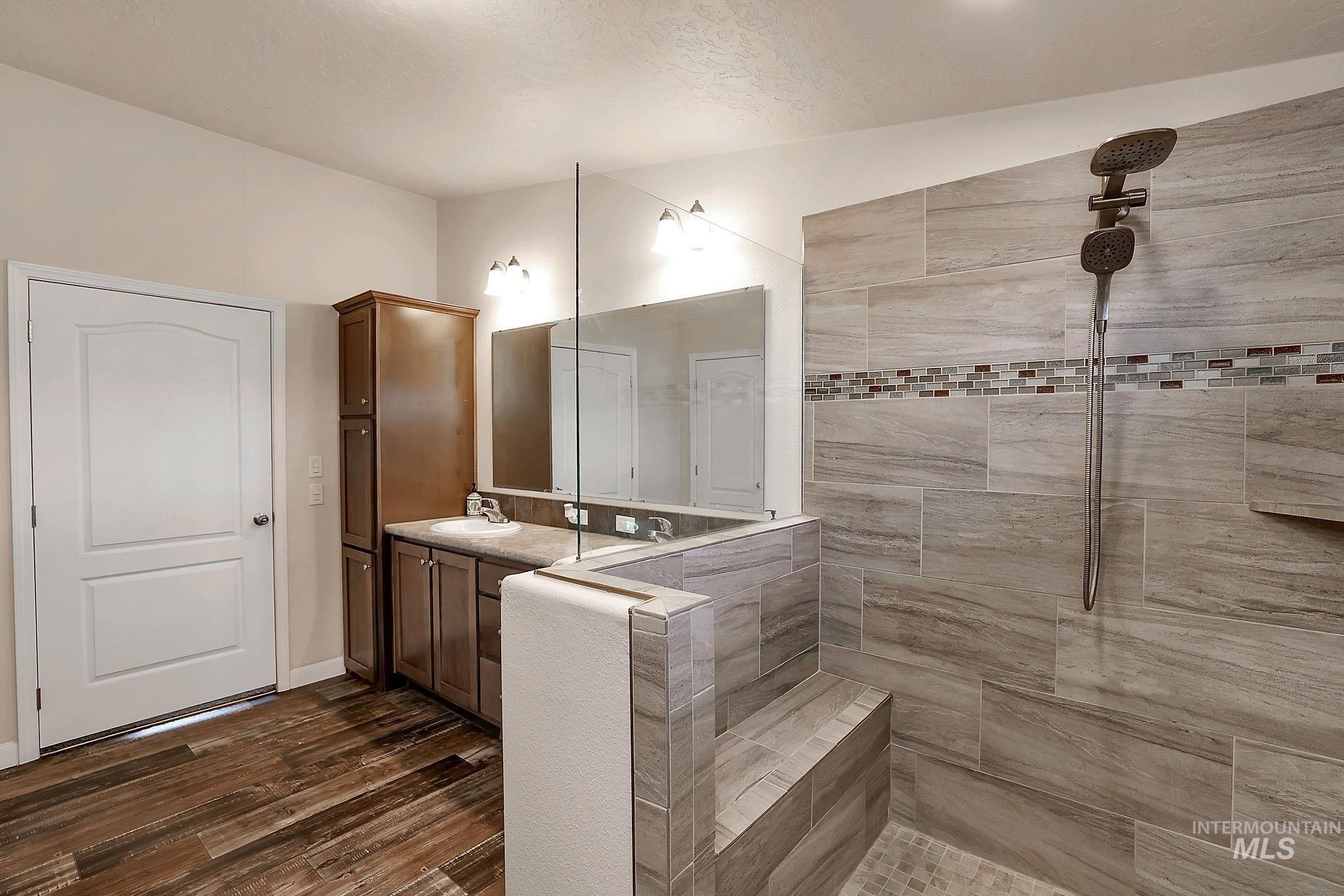 Bathroom with vanity, dark wood finished floors, walk in shower, and a textured ceiling
