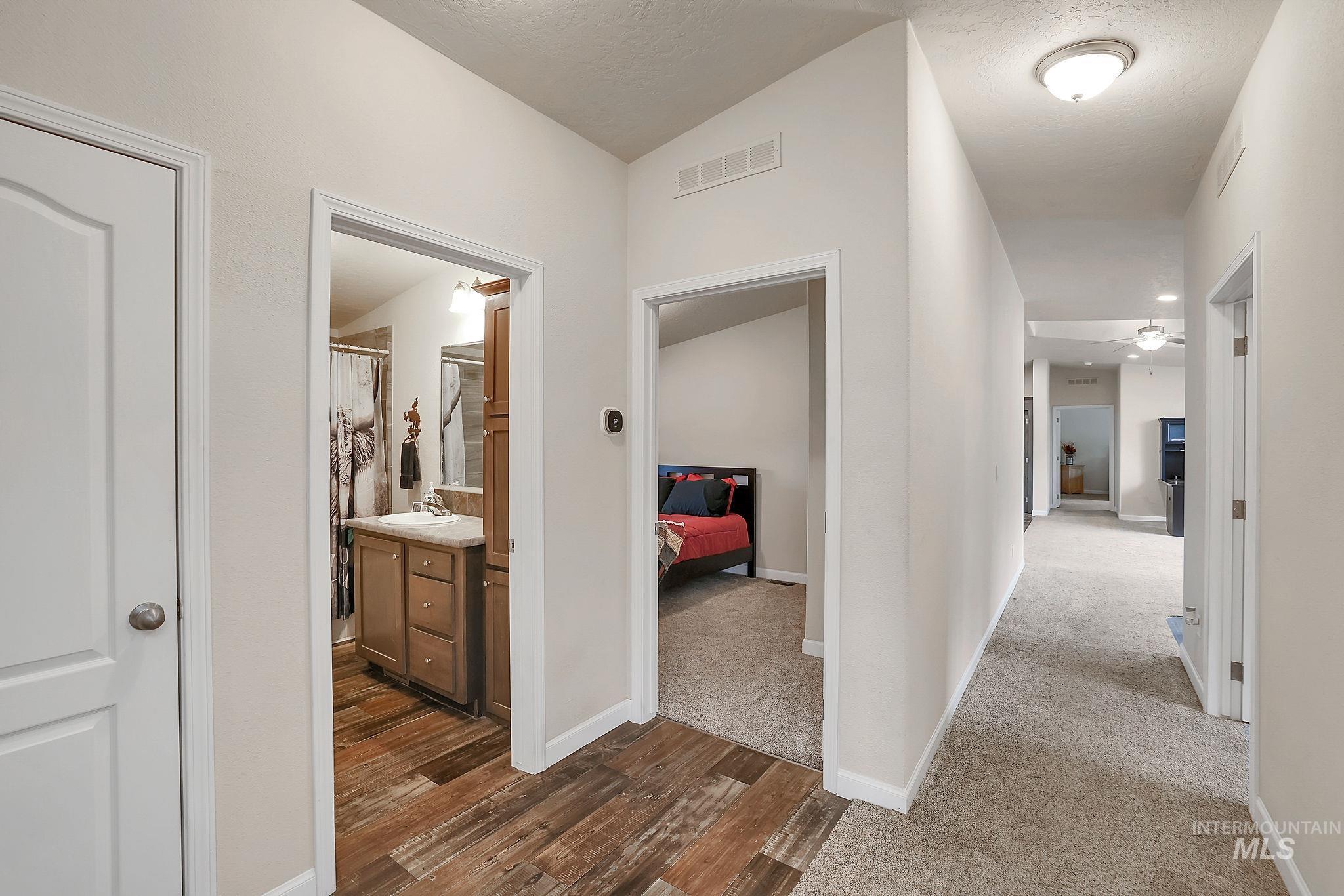 Hall with dark wood-style flooring, lofted ceiling, and a textured ceiling