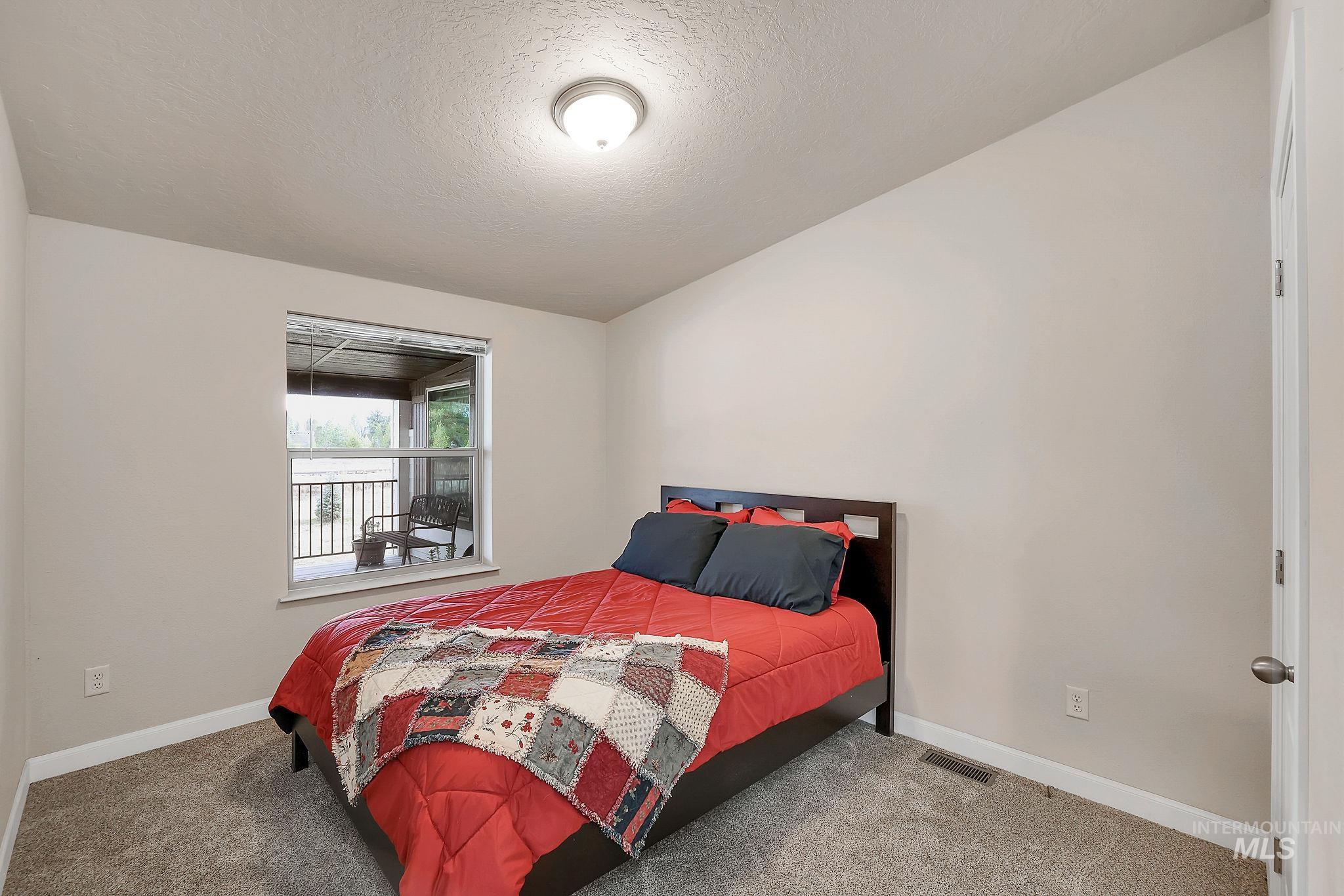 Carpeted bedroom featuring a textured ceiling and baseboards