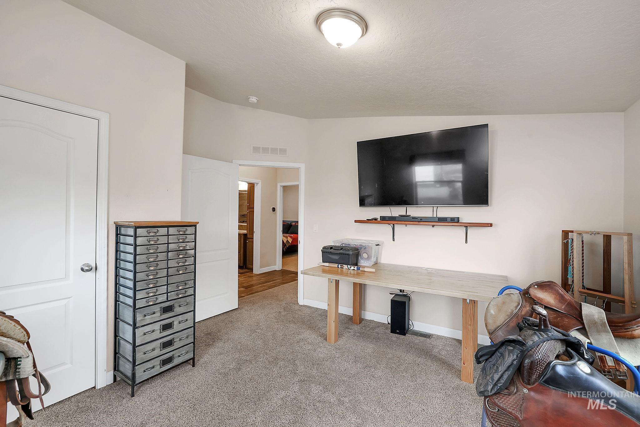 Office with light colored carpet, a textured ceiling, and vaulted ceiling
