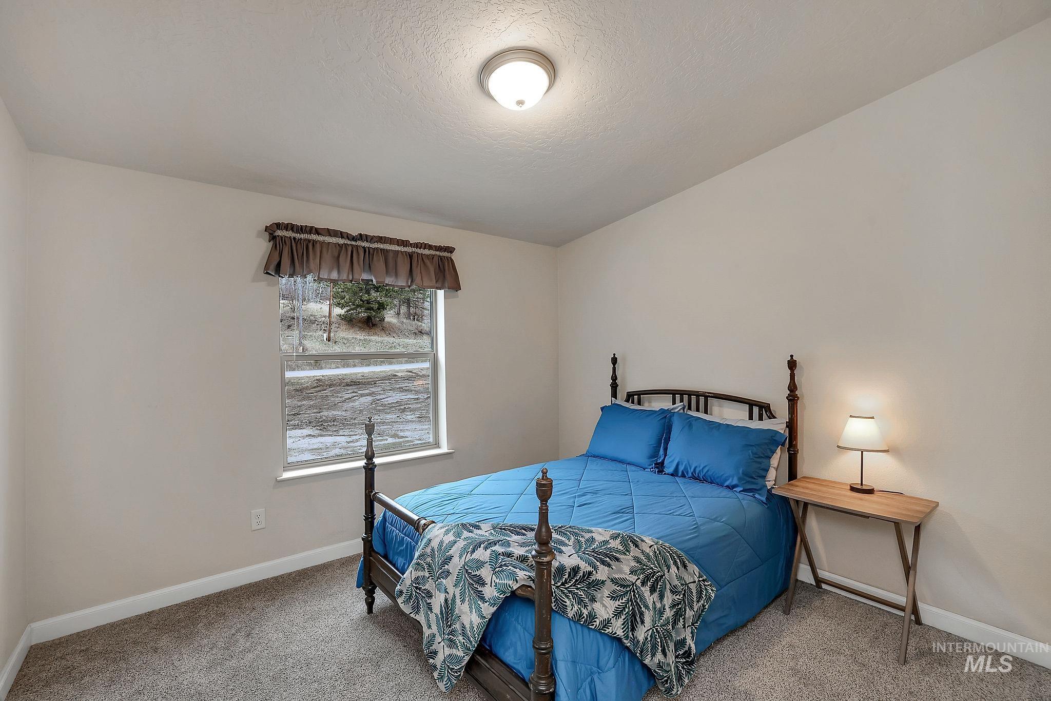 Carpeted bedroom featuring baseboards and a textured ceiling